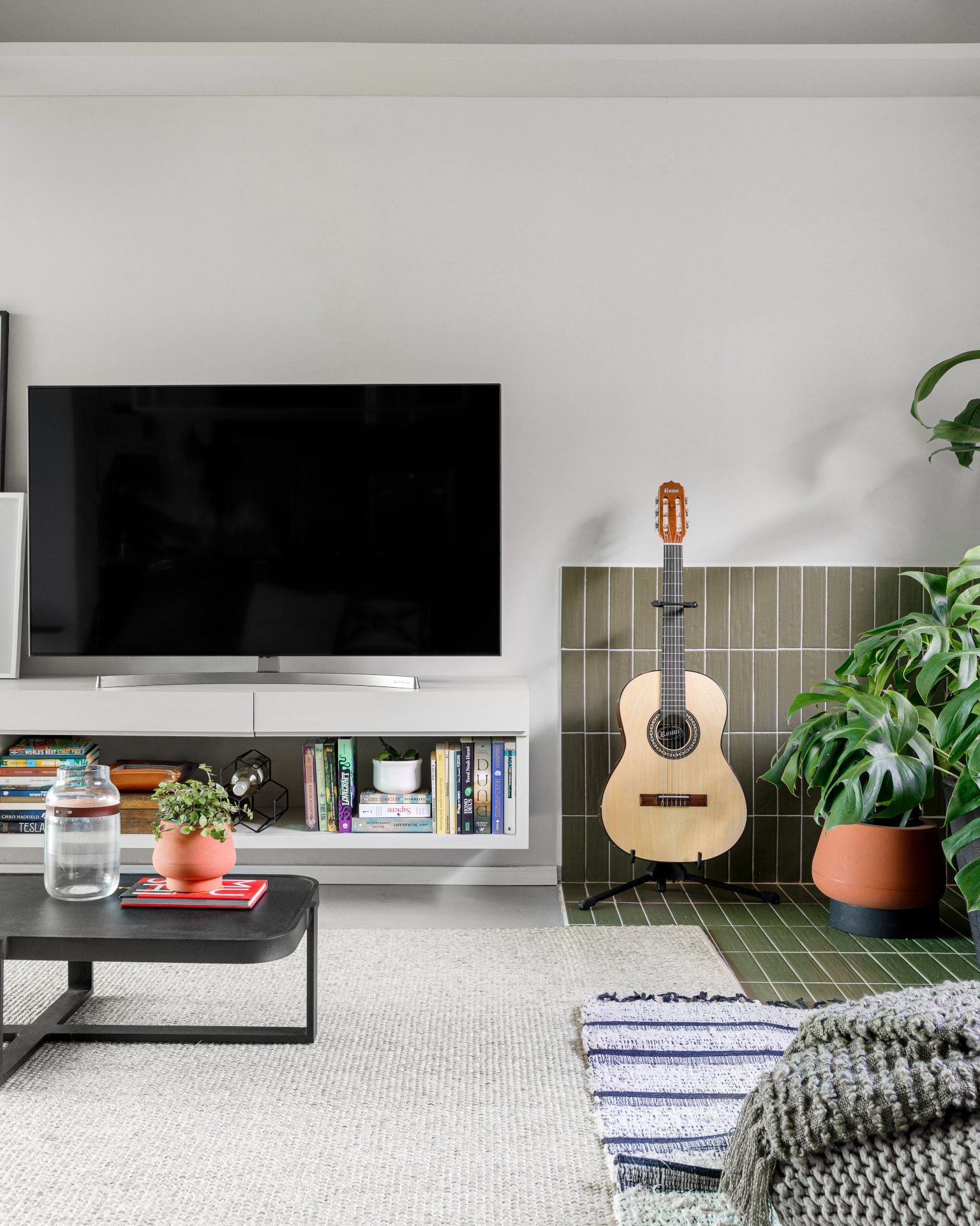 Sala com revestimento de parede verde e violão