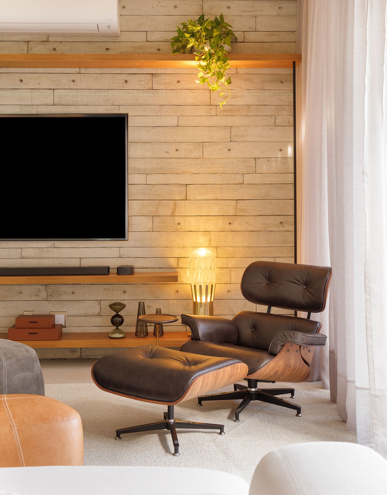 Cadeira Eames Lounge é utilizada no projeto em uma sala de estar