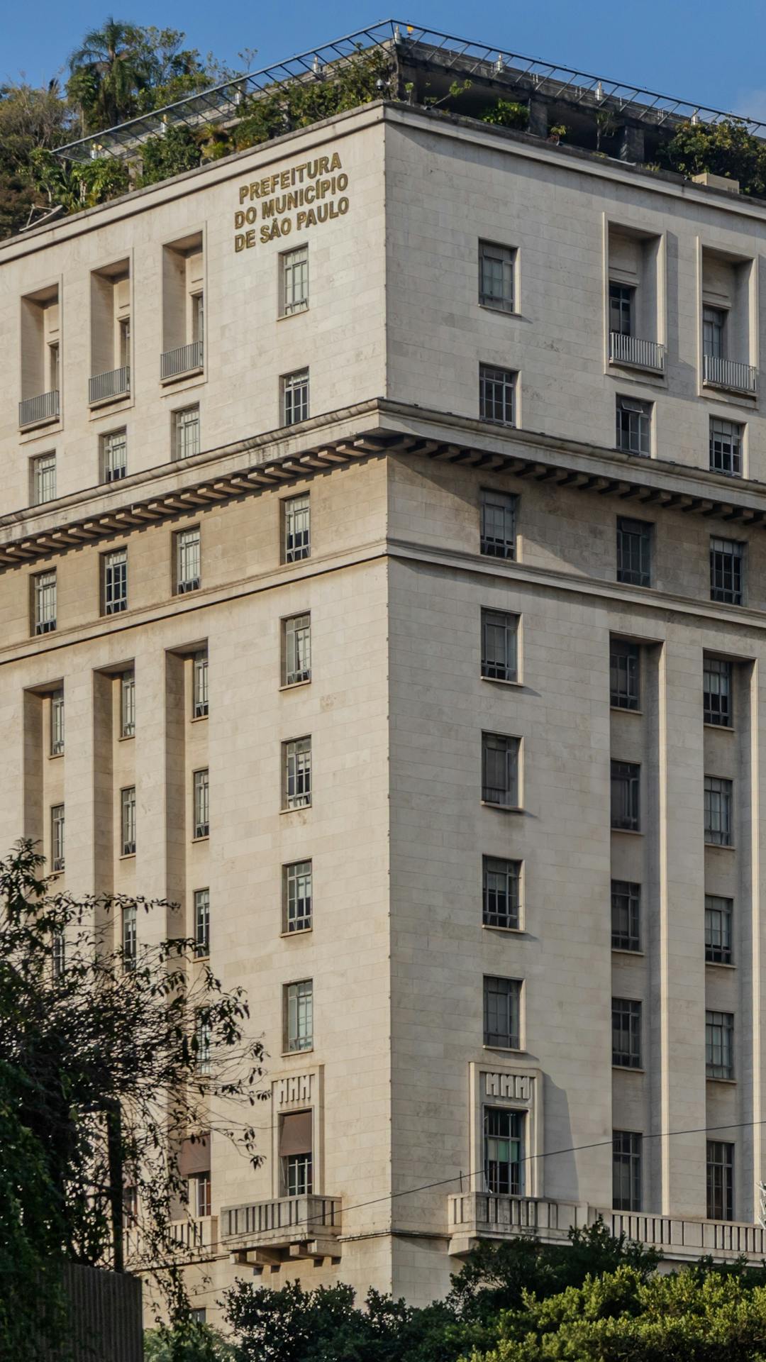 Edifício Matarazzo em São Paulo, com fachada imponente de linhas retas e janelas simétricas, rodeado por árvores, representando o estilo neoclássico italiano