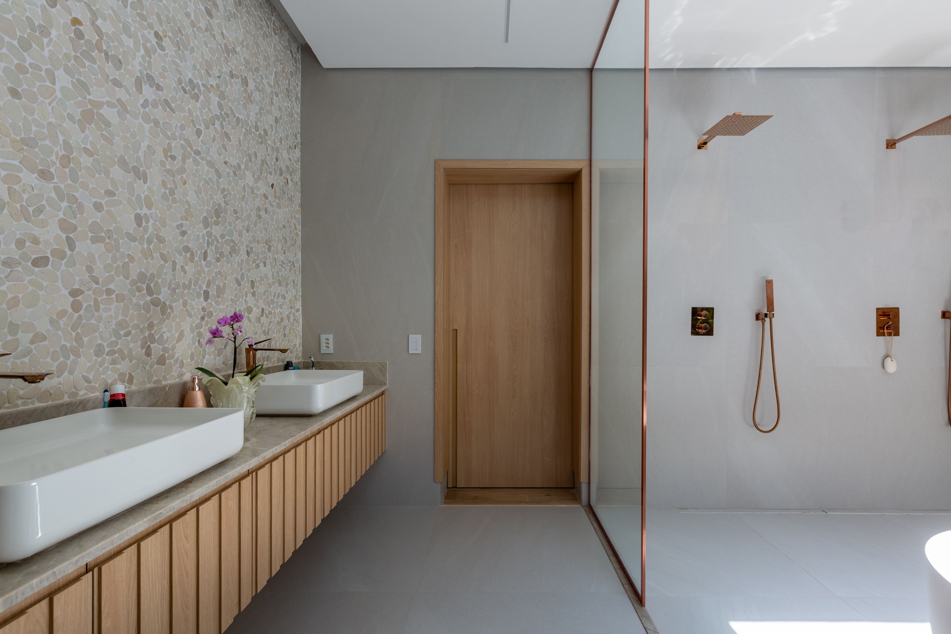 Banheiro com revestimento em porcelanato neutro e metais acobreados