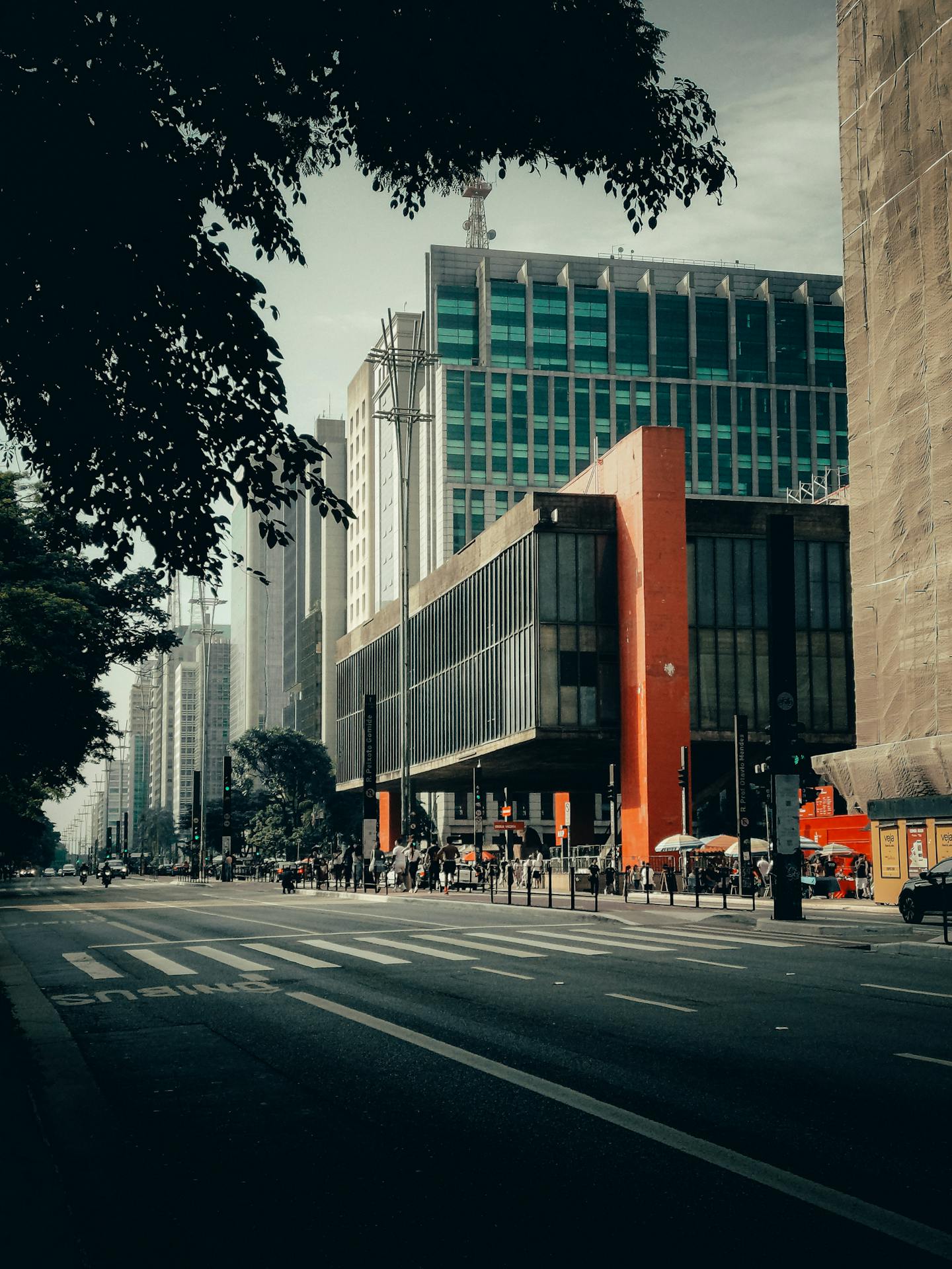 Vista da Avenida Paulista com destaque para o MASP, edifício modernista com estrutura em concreto aparente e grandes pilares vermelhos que sustentam o vão livre