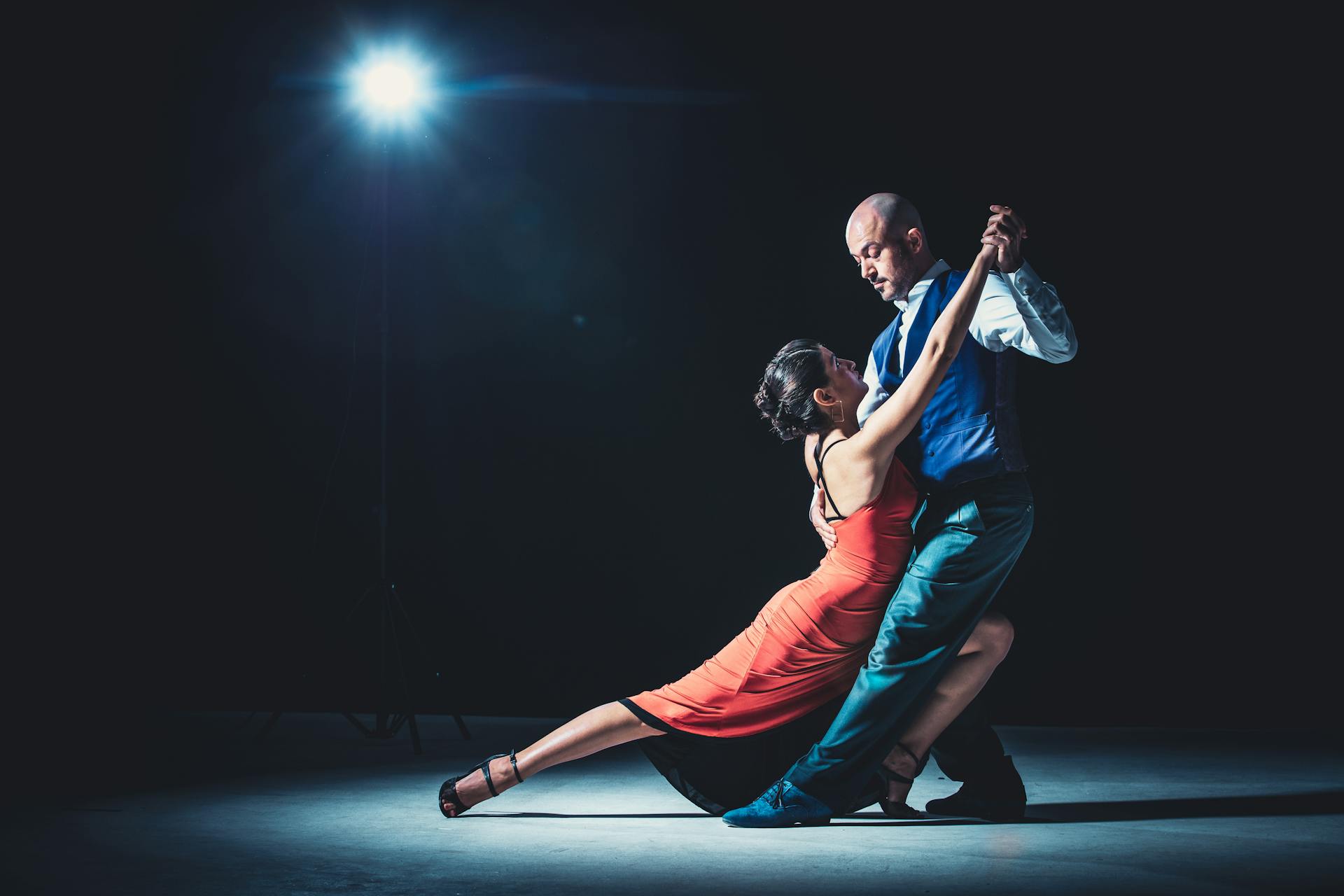 Sob o foco dramático da luz, um casal traduz em gestos e passos a essência da dança cênica
