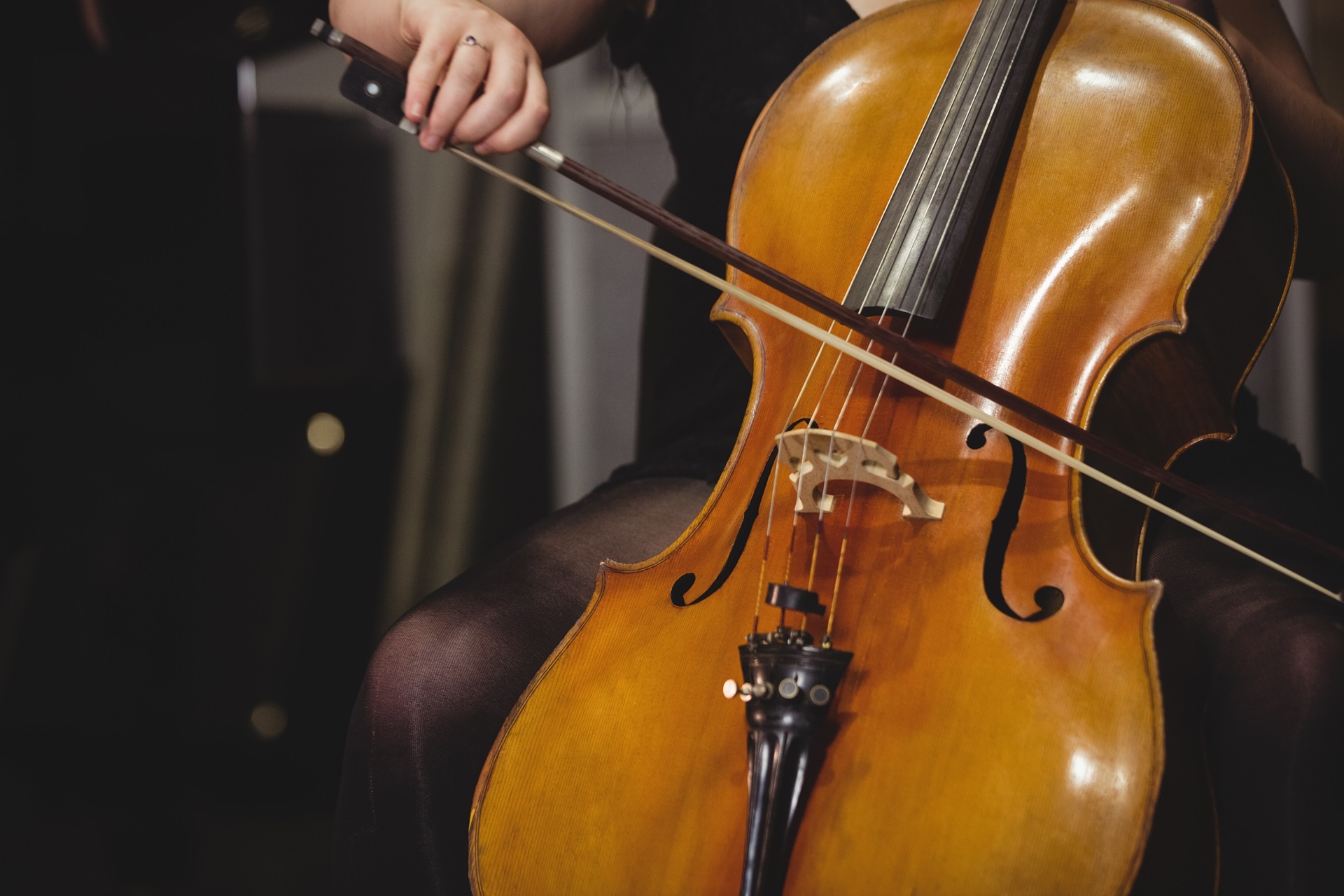 Close de uma musicista tocando violoncelo, com destaque para o movimento do arco sobre as cordas