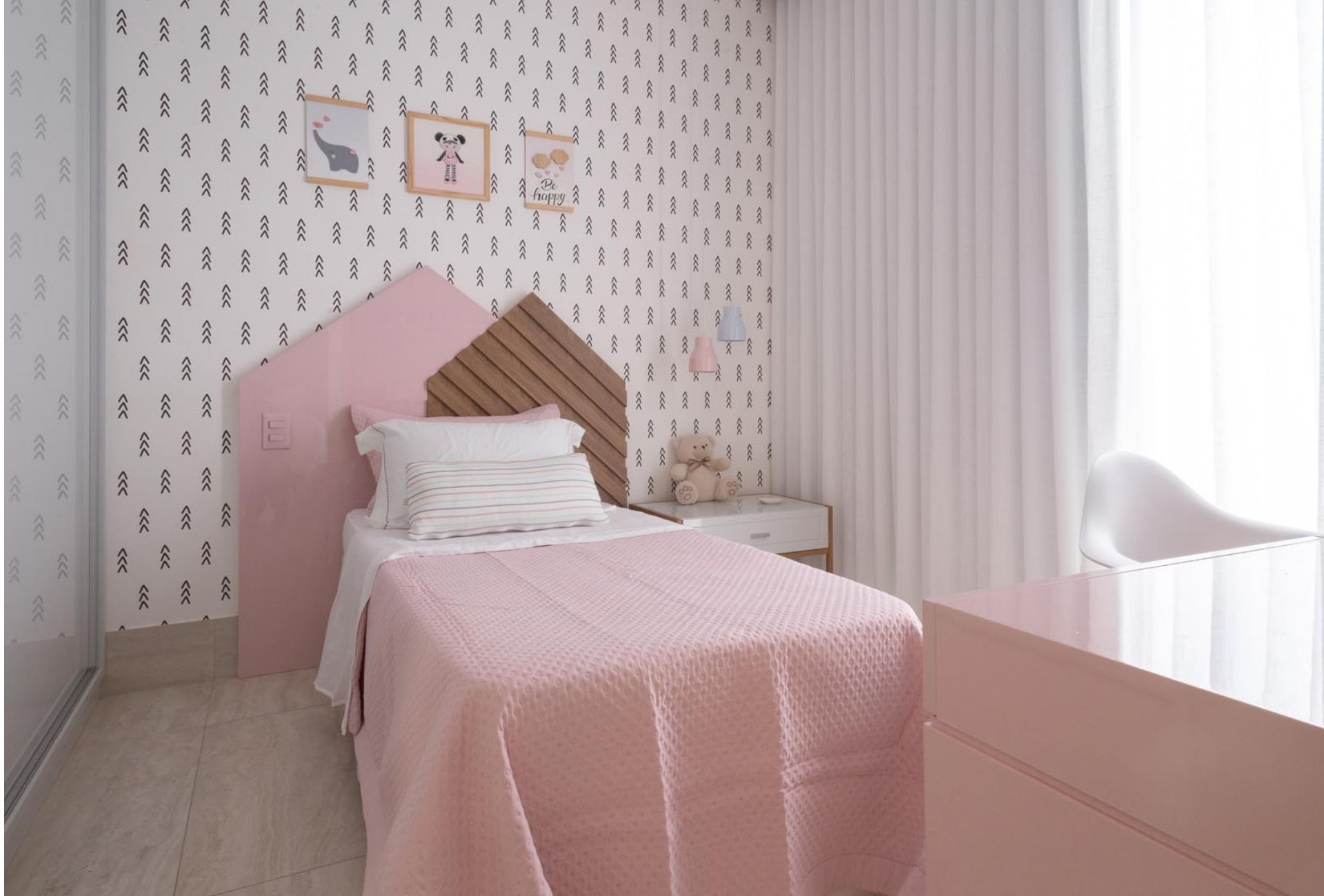 Cama de solteiro em quarto rosa e branco, com cabeceira em forma de telhado de casinha