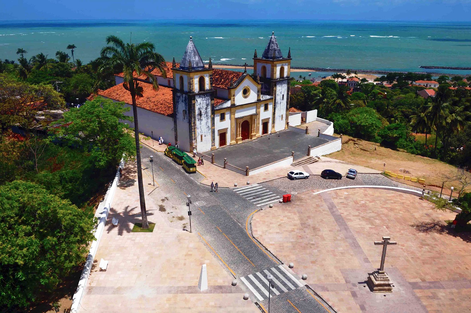 Vista frontal da Catedral de São Salvador do Mundo (Igreja da Sé), Olinda (PE): fachada com três portas em madeira ladeadas por colunas jônicas, duas torres sineiras e frontispício em estilo colonial maneirista. No interior, destaca-se o túmulo de Dom Hélder Câmara, arcebispo emérito de Recife e Olinda