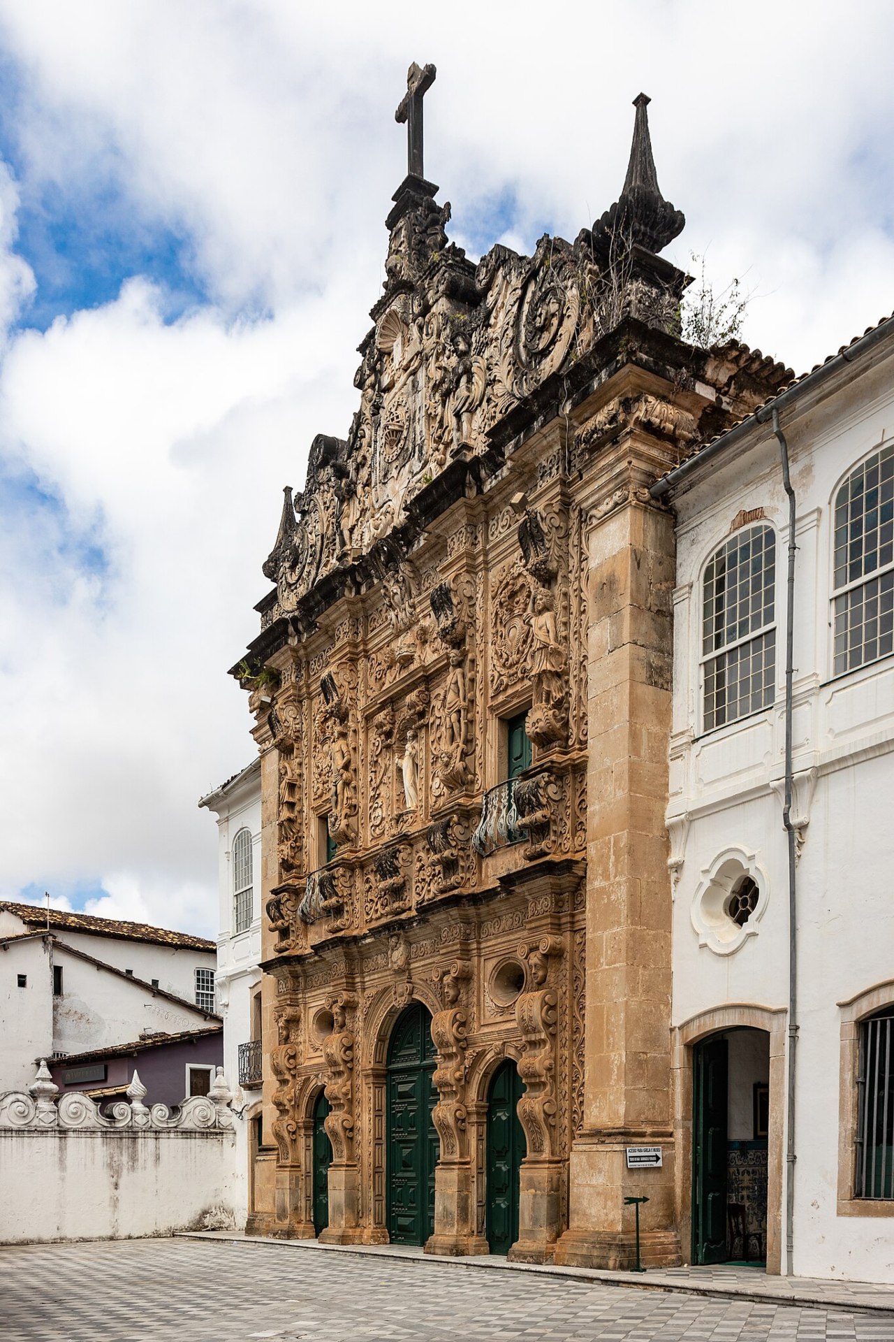 Fachada frontal da Igreja da Ordem Terceira de São Francisco, Salvador (BA): portão central de arenito decorado com ricos altos-relevos barrocos em estilo plateresco, nicho com imagem de São Francisco em mármore, ornamentos como sereias, coroa de espinhos e inscrições religiosas, ladeada por portas laterais