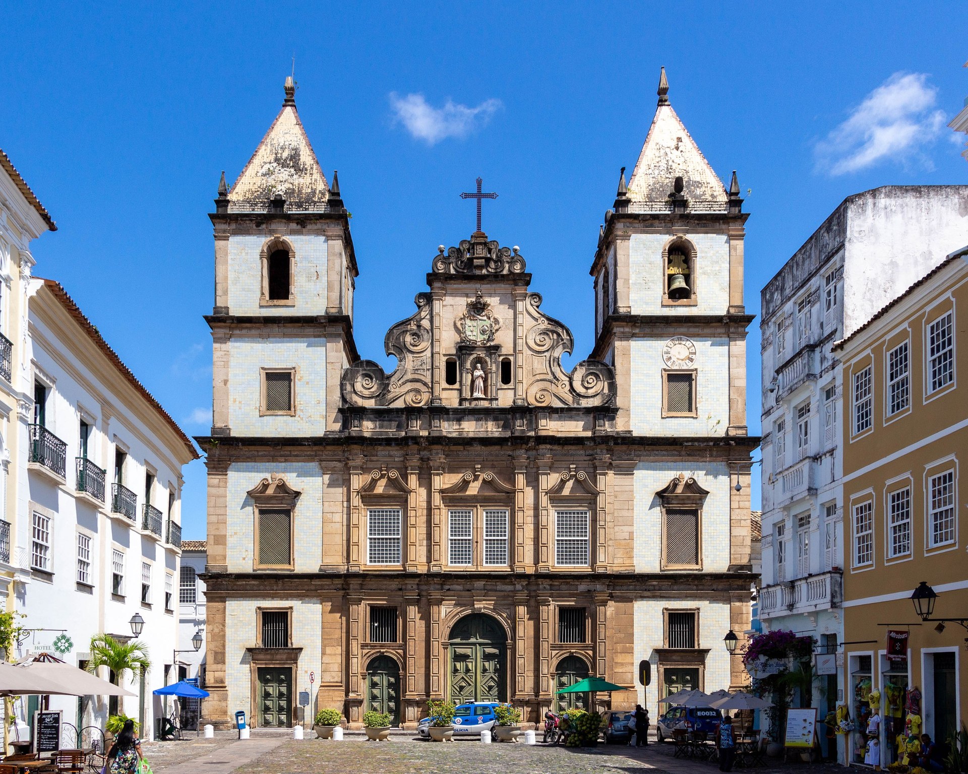 Fachada frontal da Igreja e Convento de São Francisco, em Salvador (BA): construção colonial com duas torres sineiras e frontão central triangular; fachada em pedra arenito de tonalidade clara, nicho com imagem de São Francisco de Assis e detalhes arquitetônicos com volutas e arcos, situada em praça pública