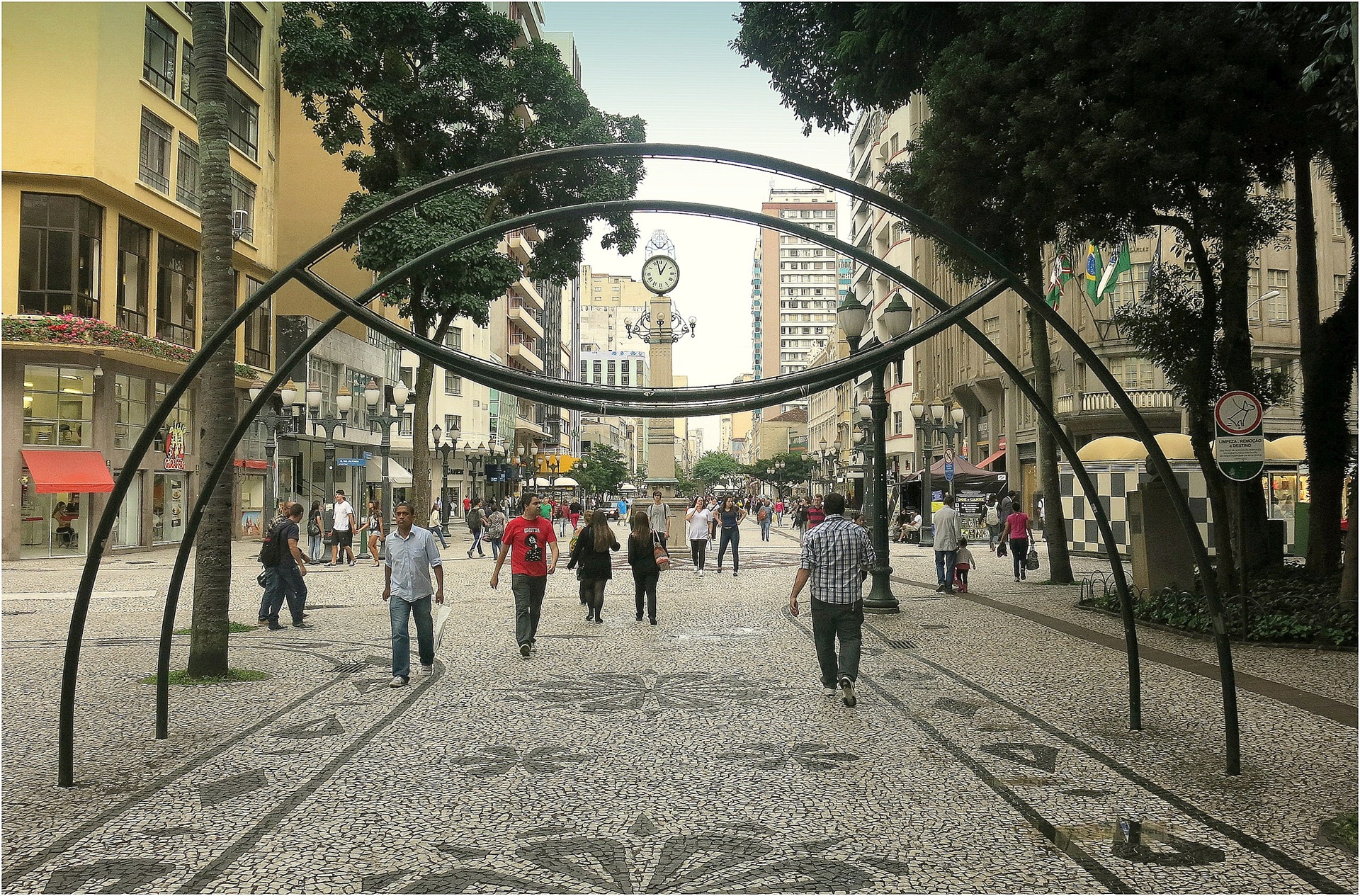 Calçadão movimentado no centro urbano, com pessoas caminhando entre prédios históricos