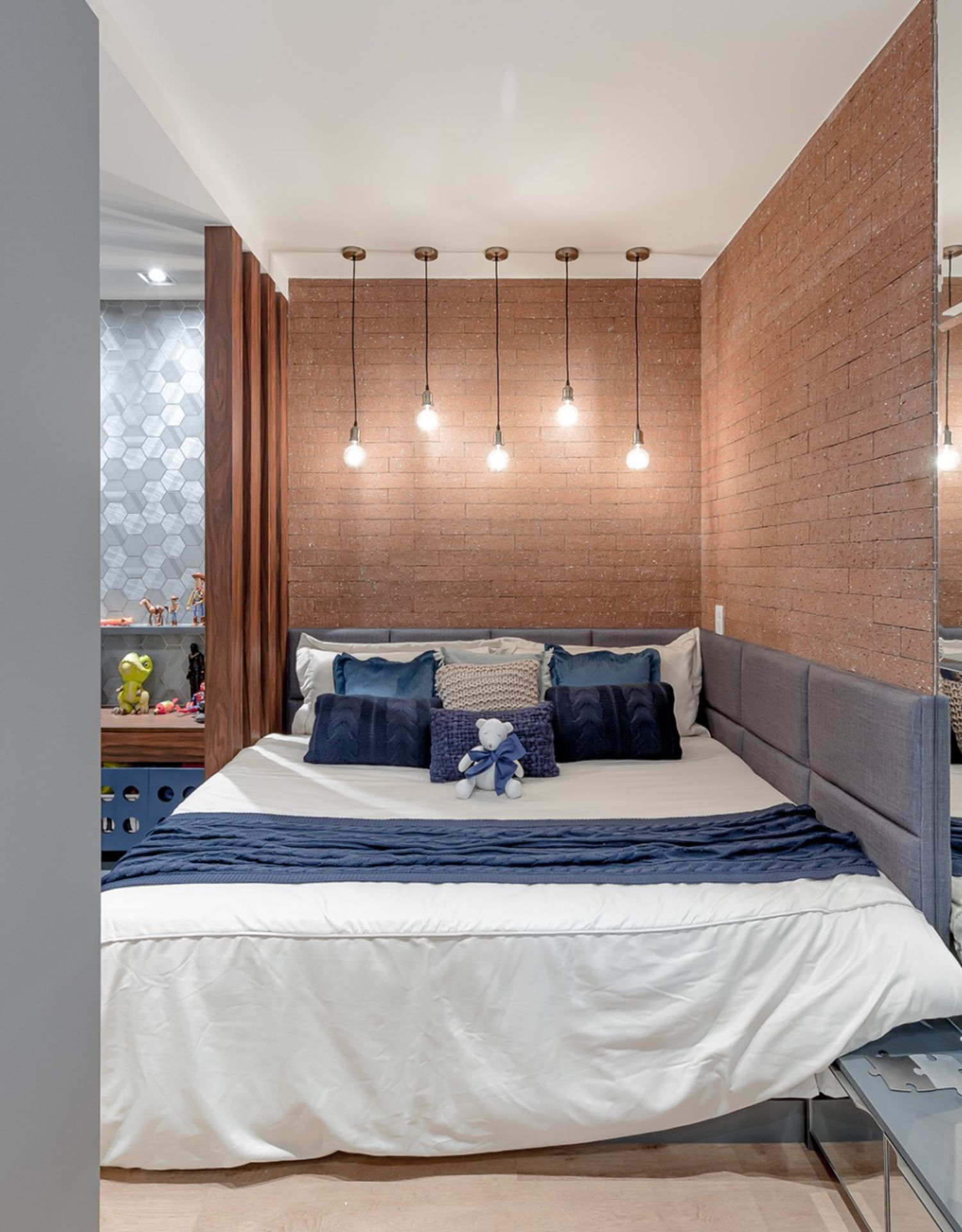 Quarto de adolescente com cama ampla e parede de tijolinhos