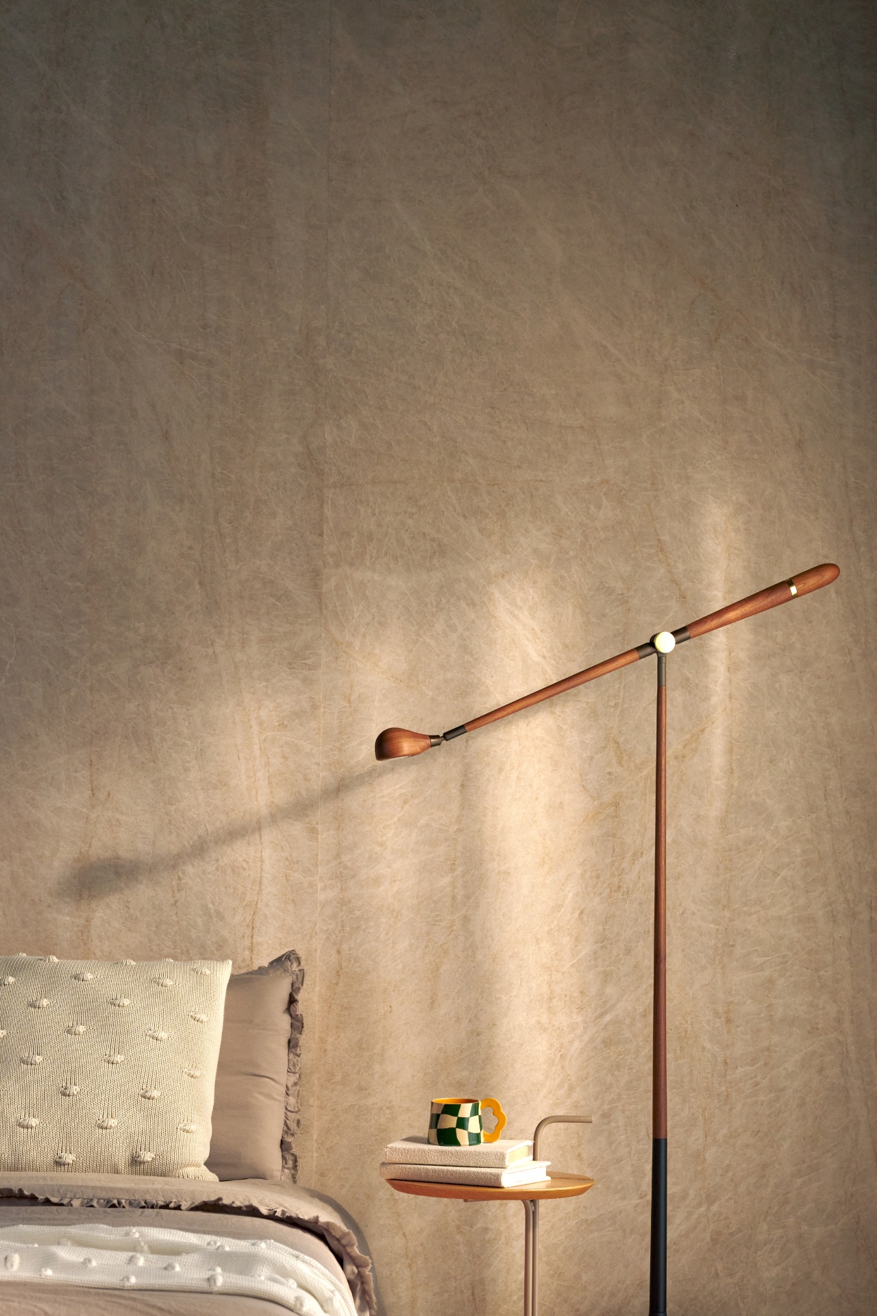 Ambiente acolhedor com cama em tons neutros, luminária de piso em madeira e parede revestida em acabamento taupe com veios sutis