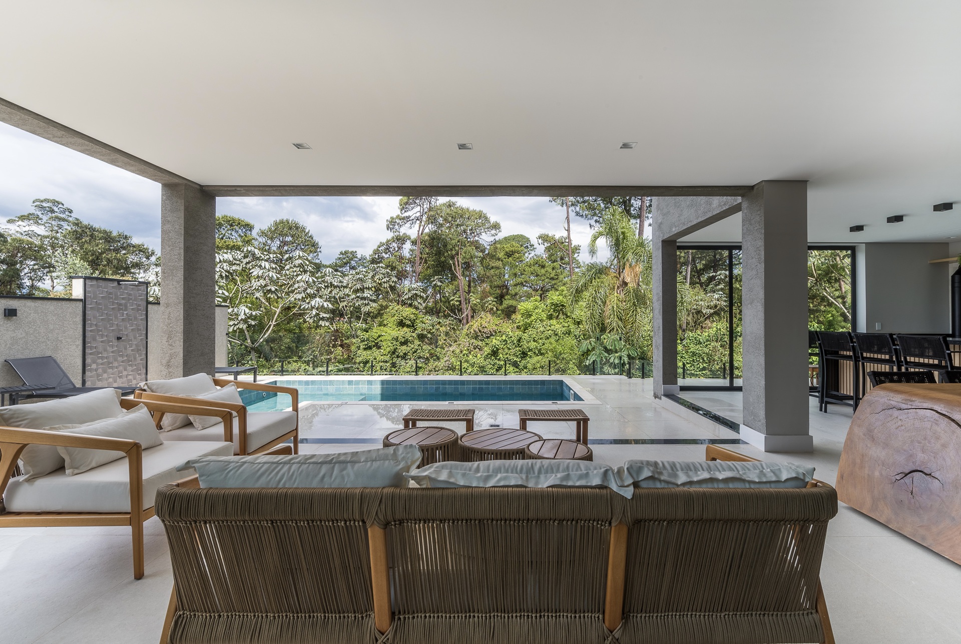 Área externa integrada à natureza, com móveis leves e piscina, exemplifica a arquitetura slow, que privilegia bem-estar e serenidade