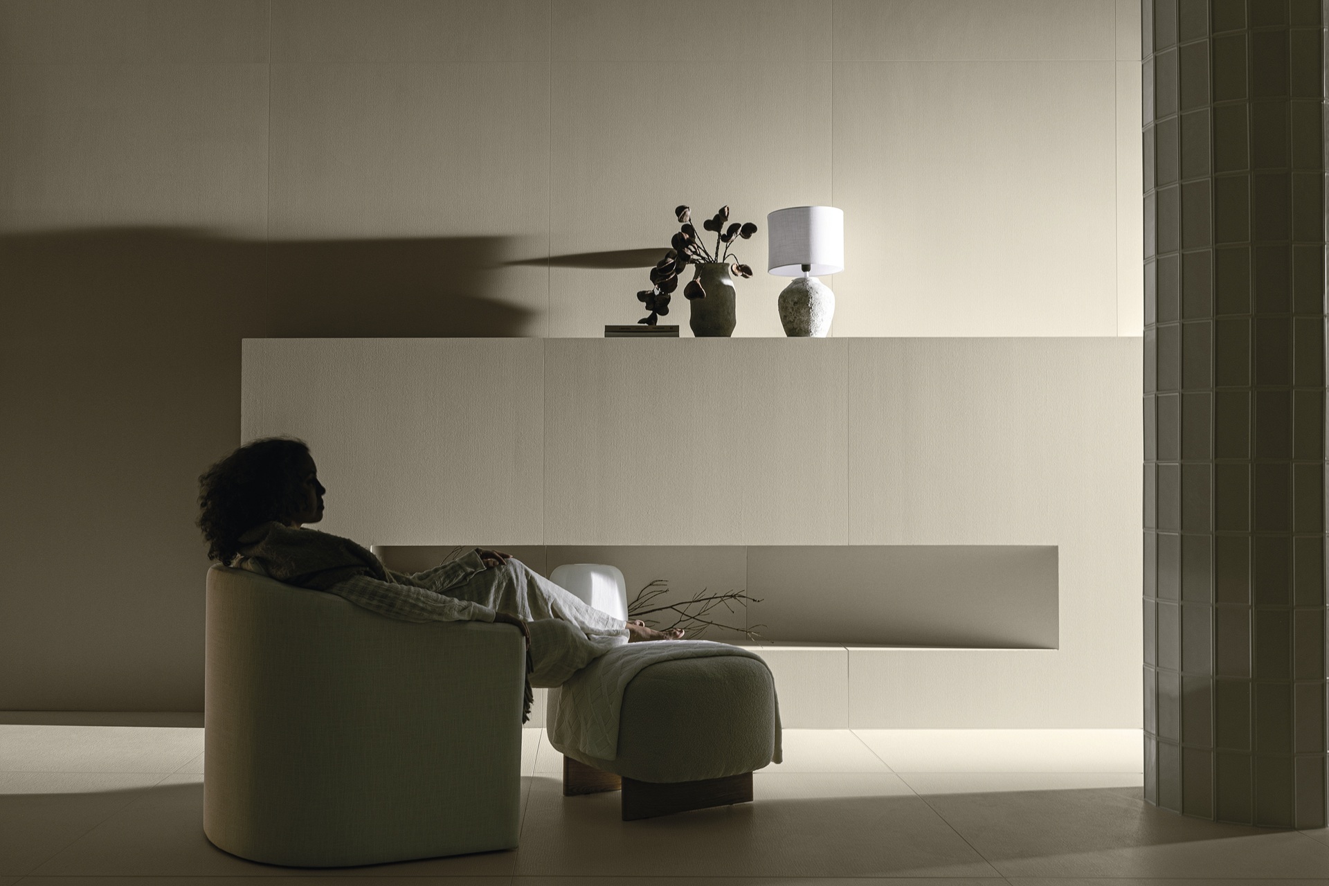 Pessoa relaxa em poltrona em ambiente minimalista, com luz suave e decoração clean, transmitindo a essência do slow living