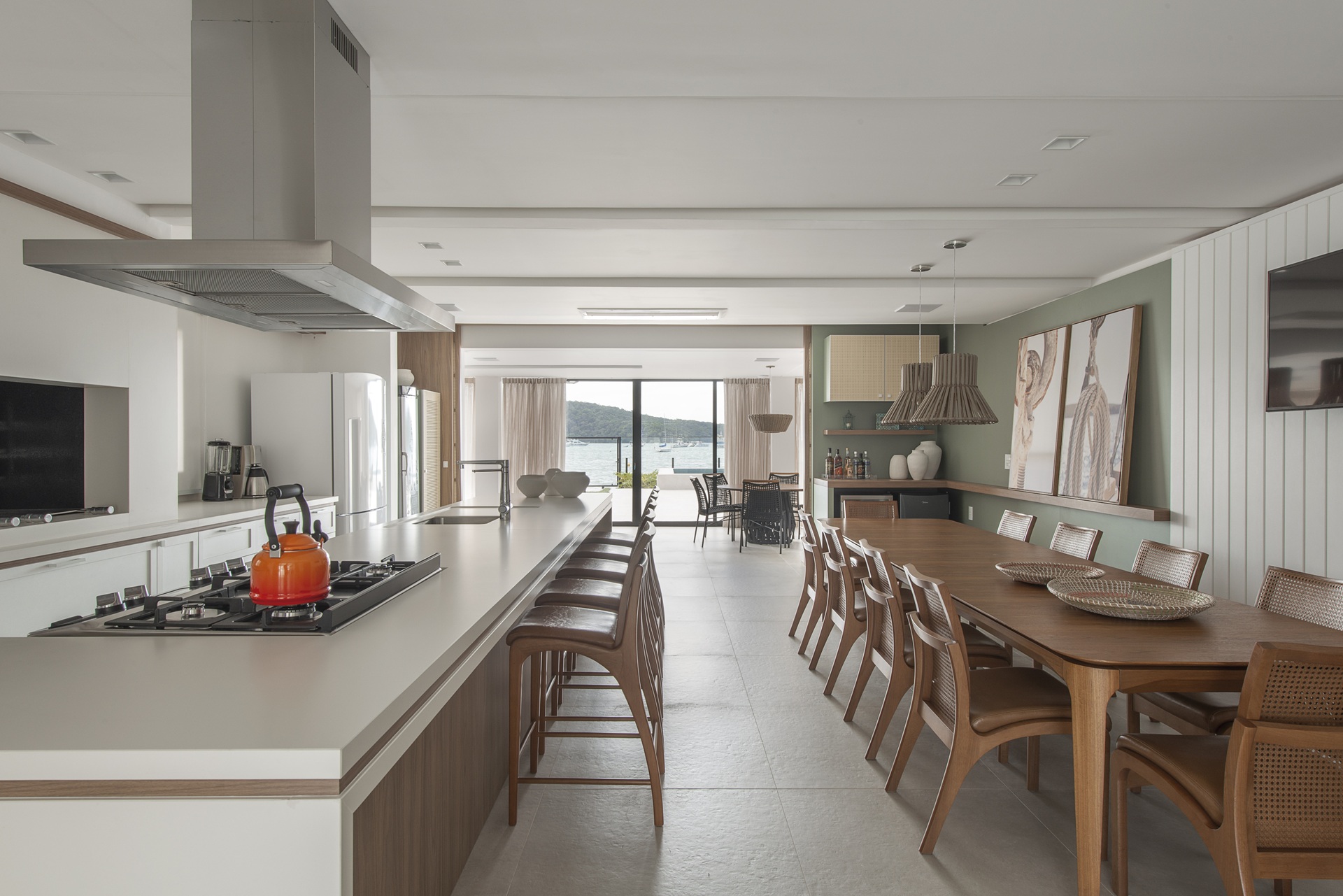 Cozinha gourmet integrada a living com porta de vidro ao fundo com visto para paisagem natural