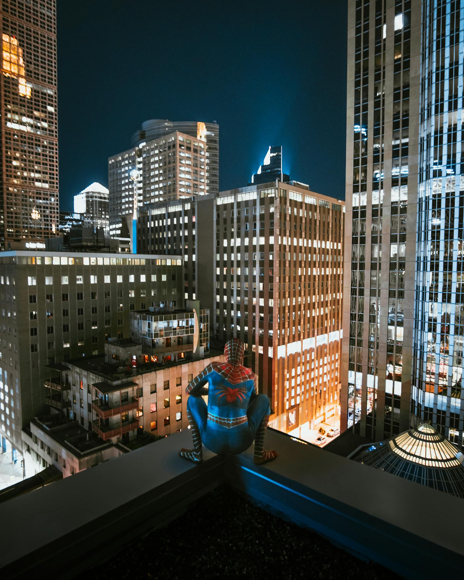 Vista noturna dos arranha-céus de Nova York, com pessoa fantasiada de Spider-Man em primeiro plano