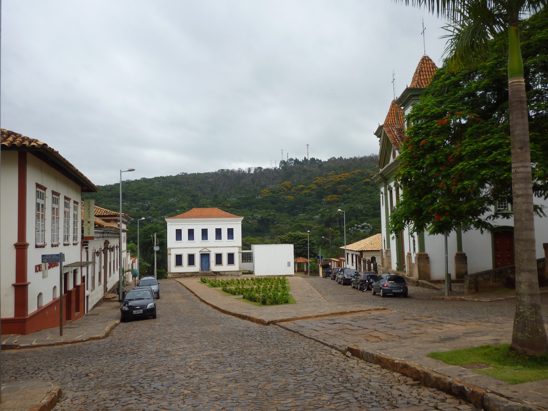 Praça da Matriz em Santa Bárbara, Minas Gerais, com casarões históricos, igreja e montanhas ao fundo