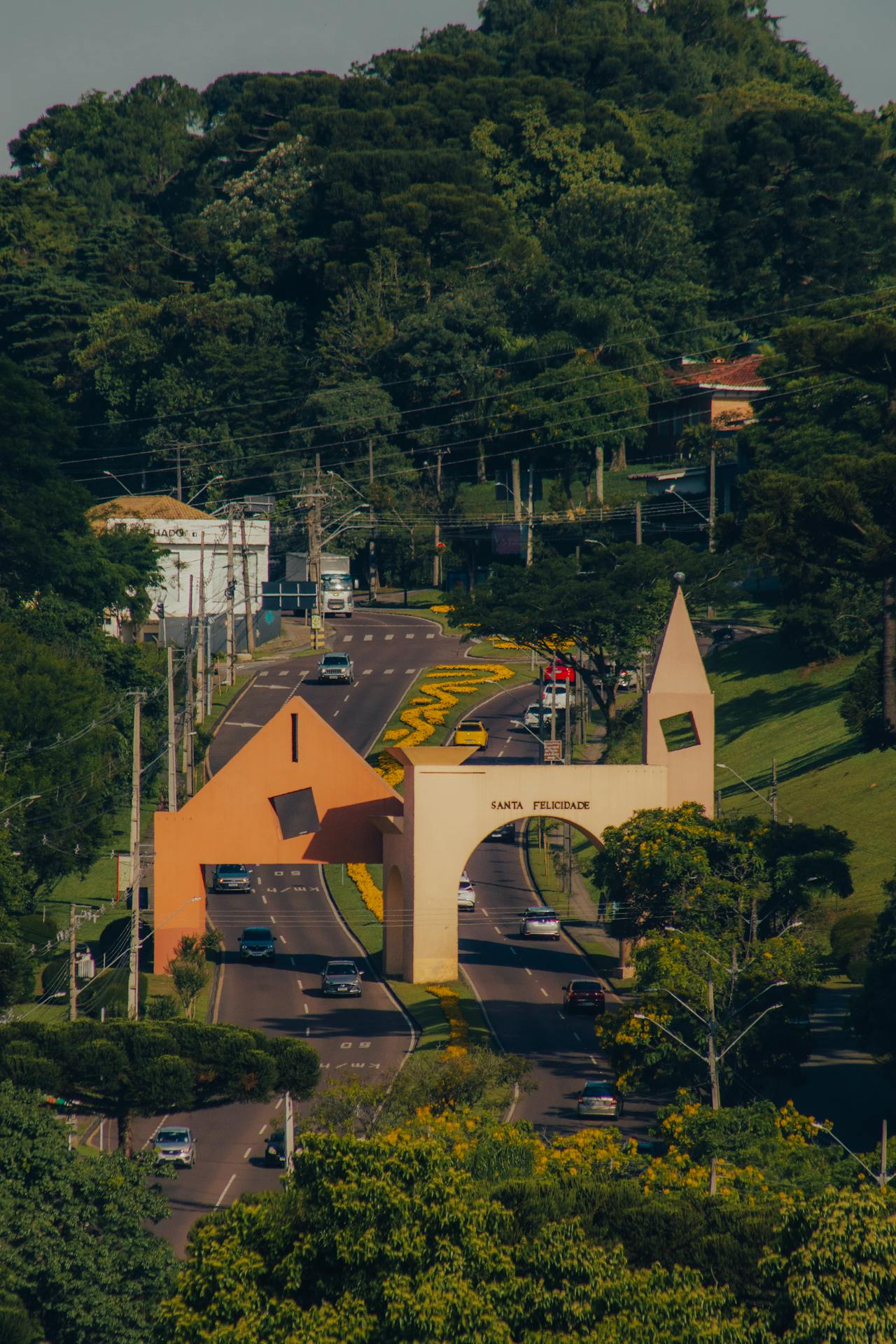 Portal do bairro Santa Felicidade, em Curitiba, com carros passando e área verde ao redor