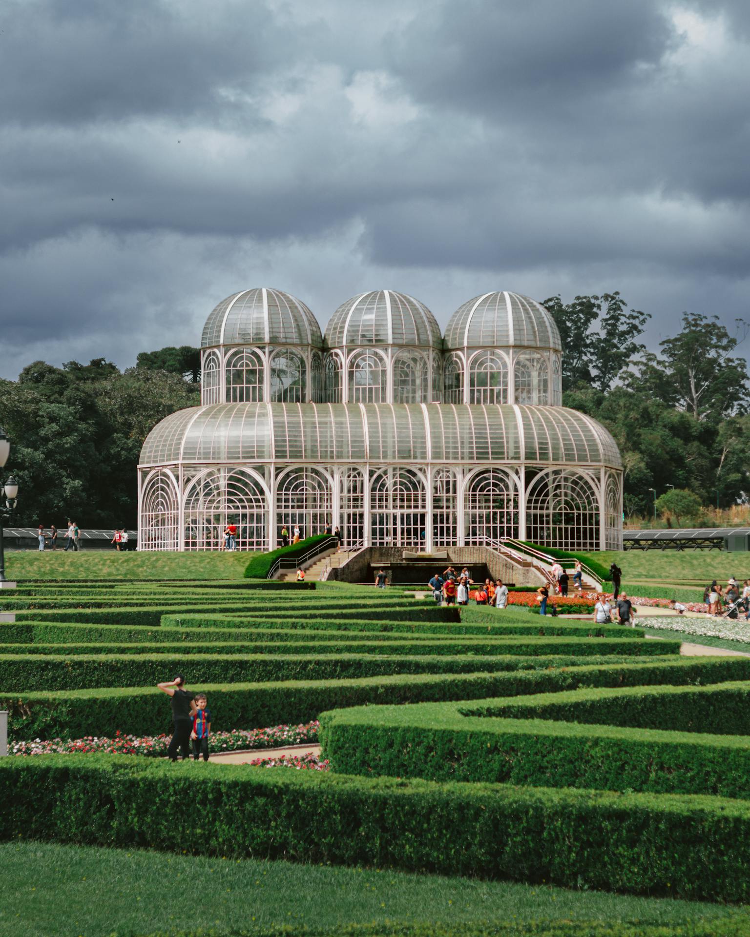 Vista do Jardim Botânico de Curitiba, com estufa de vidro e jardins geométricos ao redor