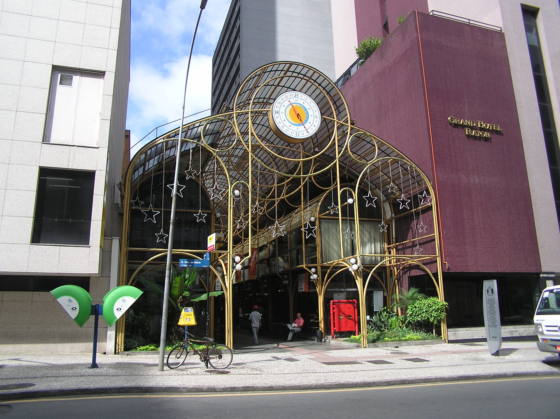 Entrada da Rua 24 Horas, em Curitiba, com estrutura metálica dourada e relógio no topo