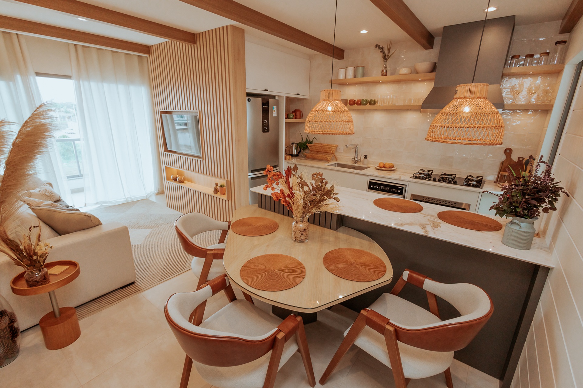 Cozinha integrada com sala, mesa de jantar com sousplats, luminárias de fibras naturais, arranjos secos e prateleiras abertas com utensílios decorativos
