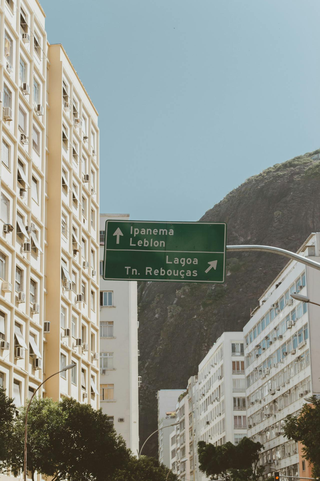 irmãos rebouças Fotografia colorida de uma rua no Rio de Janeiro, com prédios altos e uma placa verde de trânsito indicando direções para Ipanema, Leblon, Lagoa e Túnel Rebouças