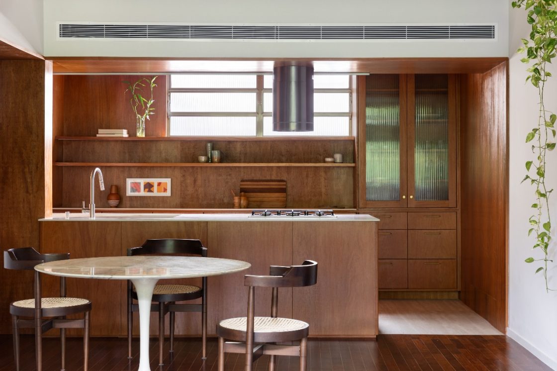 Cozinha americana com mesa de jantar redonda e revestimentos em tons terrosos