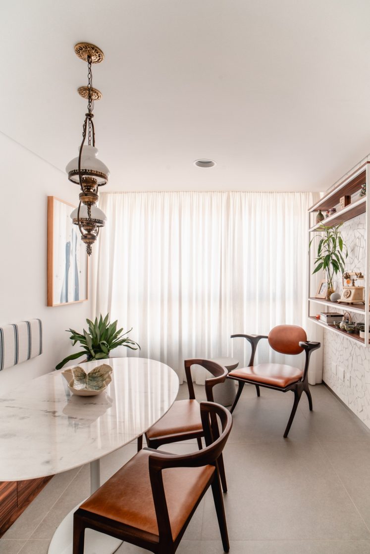 Sala de apartamento em tons claros com mesa em formato orgânico
