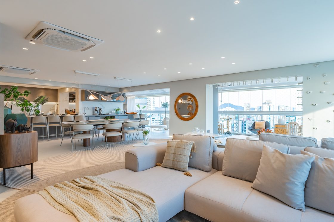 Espaço amplo e integrado em apartamento com janelas grandes e tons claros e neutros