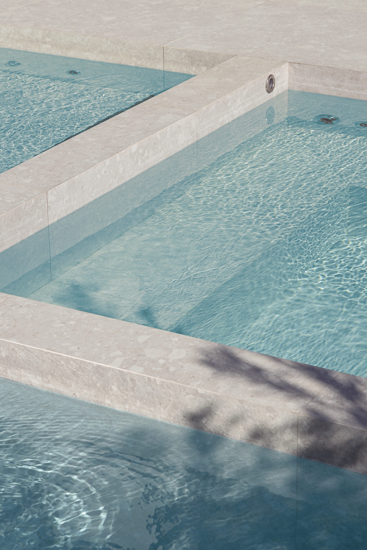 Close em piscina com revestimento que reproduz Ceppo di Gré em tom claro