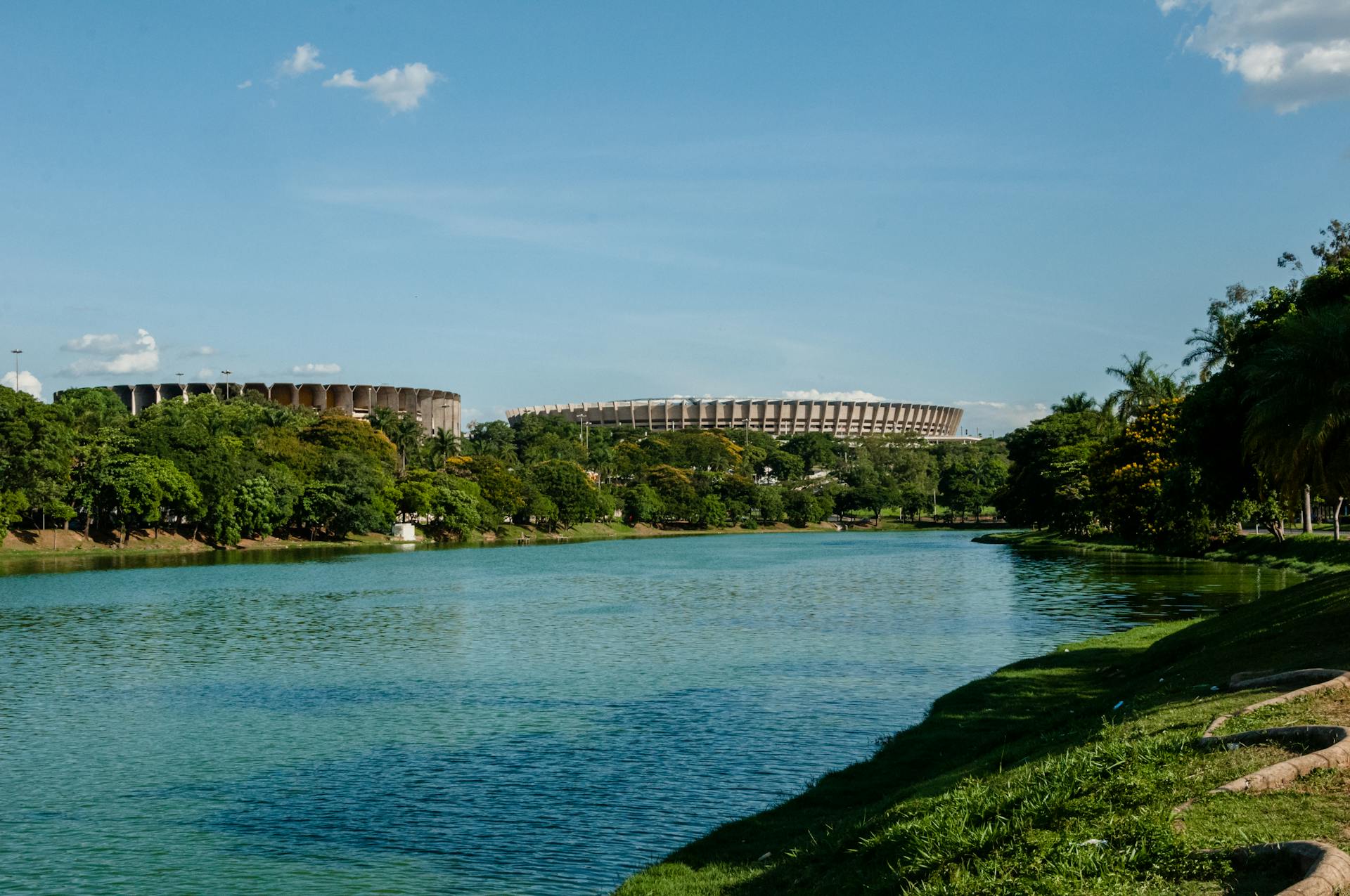 belo horizonte Vista da Lagoa da Pampulha em Belo Horizonte com vegetação abundante e os estádios Mineirão e Mineirinho ao fundo, representando o conceito de cidade-jardim.