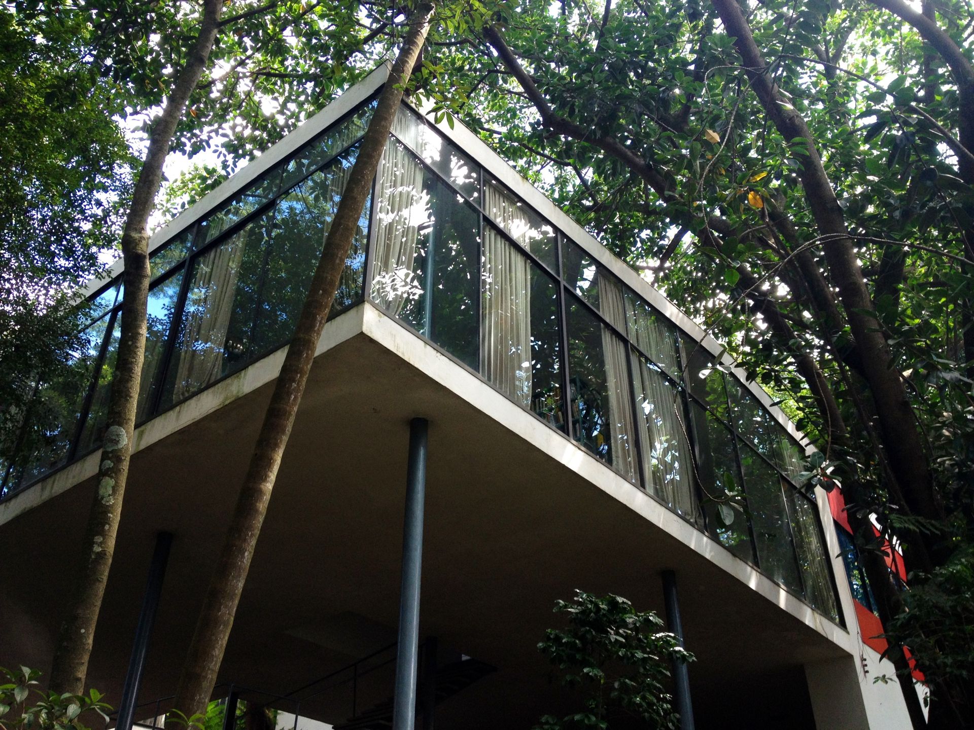 Casa de Vidro de Lina Bo Bardi, com destaque para a transparência da fachada envidraçada e os elementos naturais ao redor