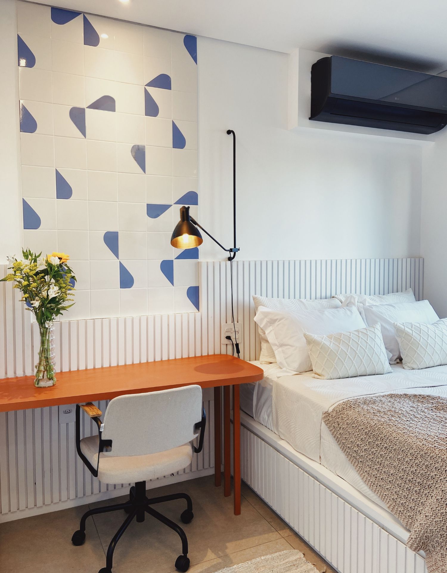 Quarto neutro com um painel artístico feito com ceramicas geométricas nas cores azul e branco