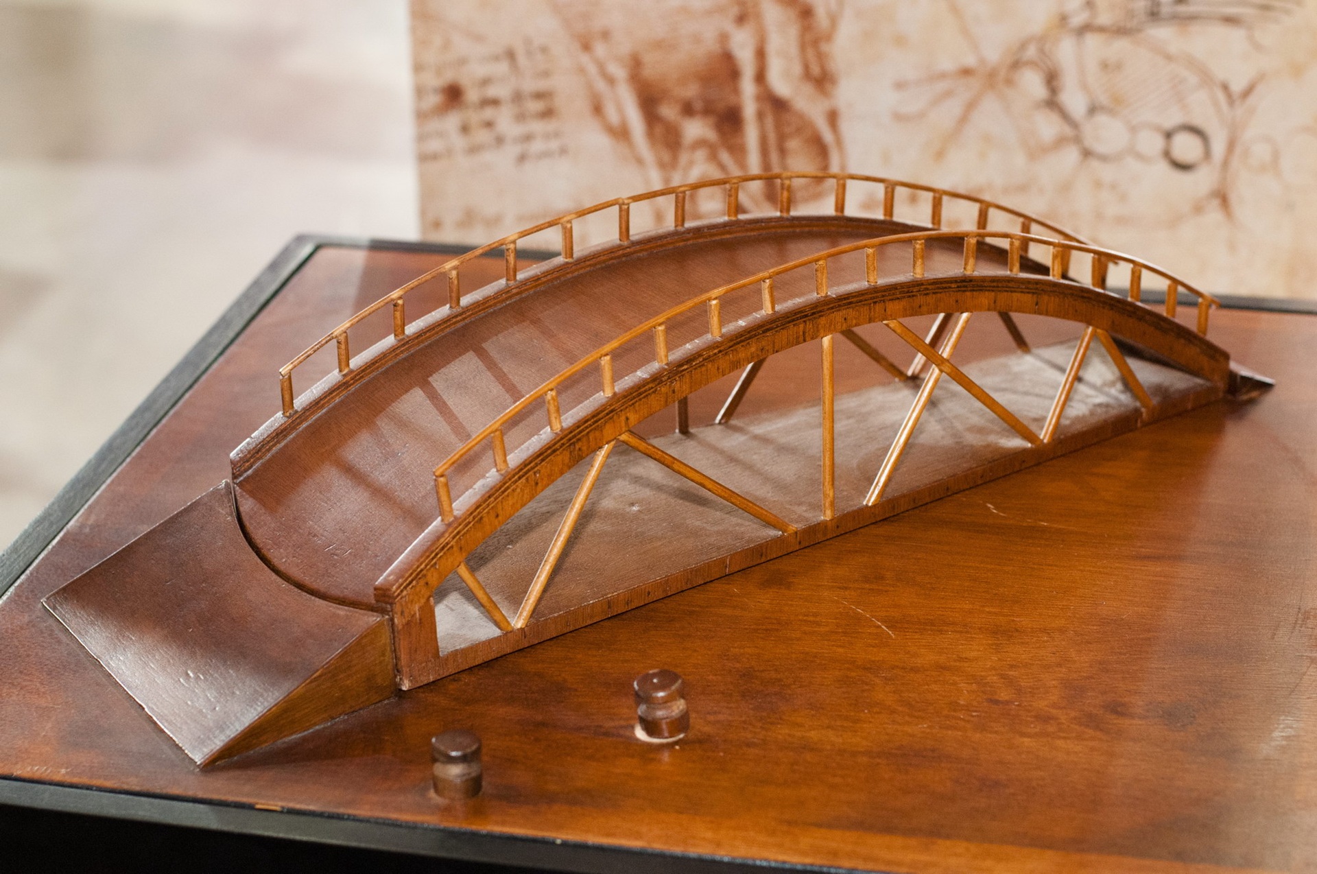 Fotografia de uma maquete em madeira da ponte autoportante projetada por Leonardo da Vinci. A estrutura arqueada é formada por peças de madeira que se encaixam sem o uso de pregos ou fixadores, sustentando-se apenas pelo equilíbrio e pela distribuição de peso