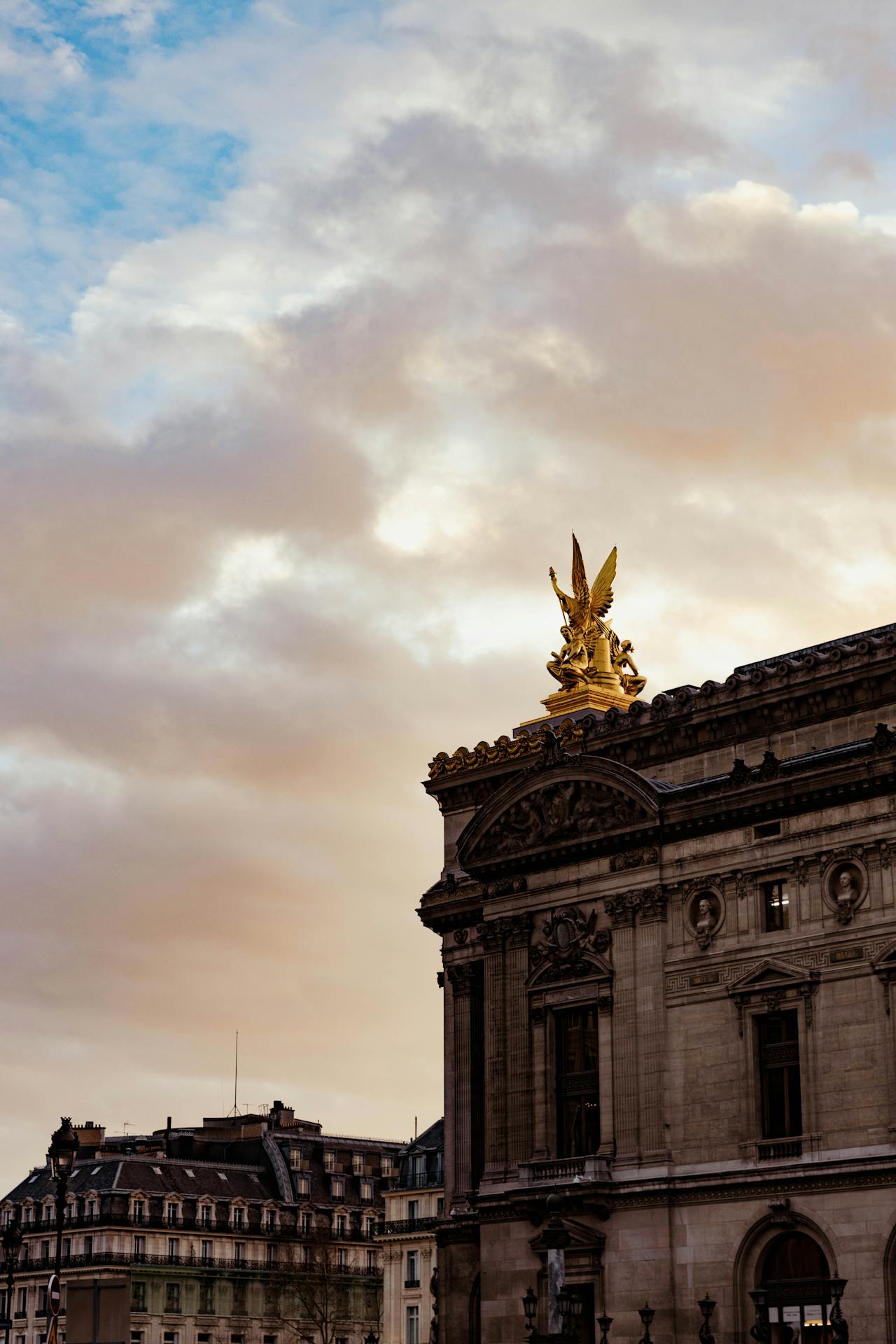 opera garnier Detalhe da fachada da Ópera Garnier, em Paris, com destaque para a escultura dourada da Harmonia no topo do edifício, iluminada pela luz suave do entardecer