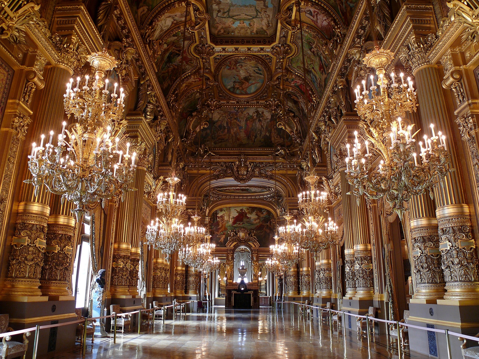 opera garnier Vista interna do Grand Foyer da Ópera Garnier, em Paris, com colunas douradas, lustres de cristal e teto ricamente pintado com cenas mitológicas