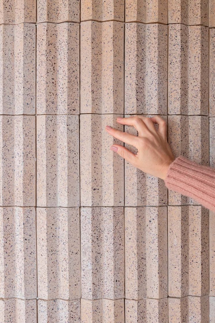 Mulher passando a mão em parede com revestimento 3D em tom terroso