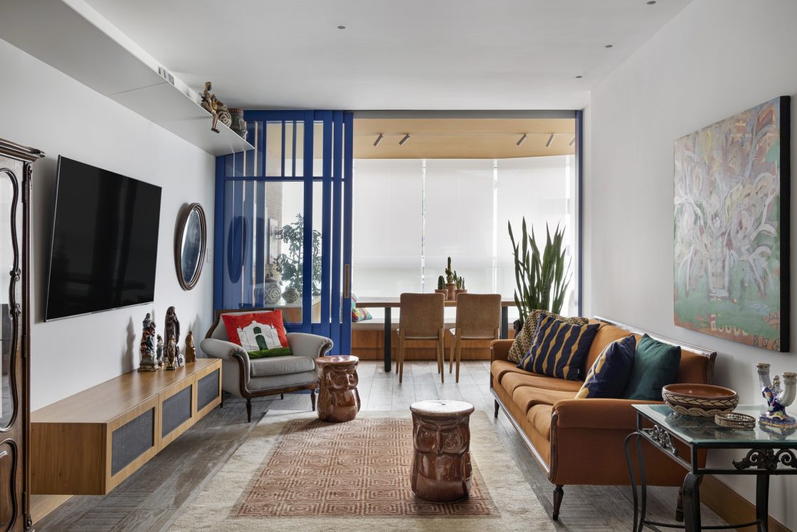 Living em tons neutros, com móveis terrosos e detalhes em azul