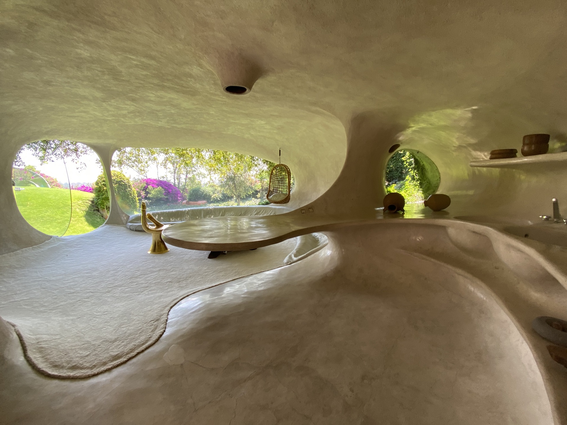 Interior da Casa Orgânica, do arquiteto mexicano Javier Senosiain. O ambiente é formado por superfícies curvas e contínuas em tons claros, com janelas amplas que se abrem para o jardim