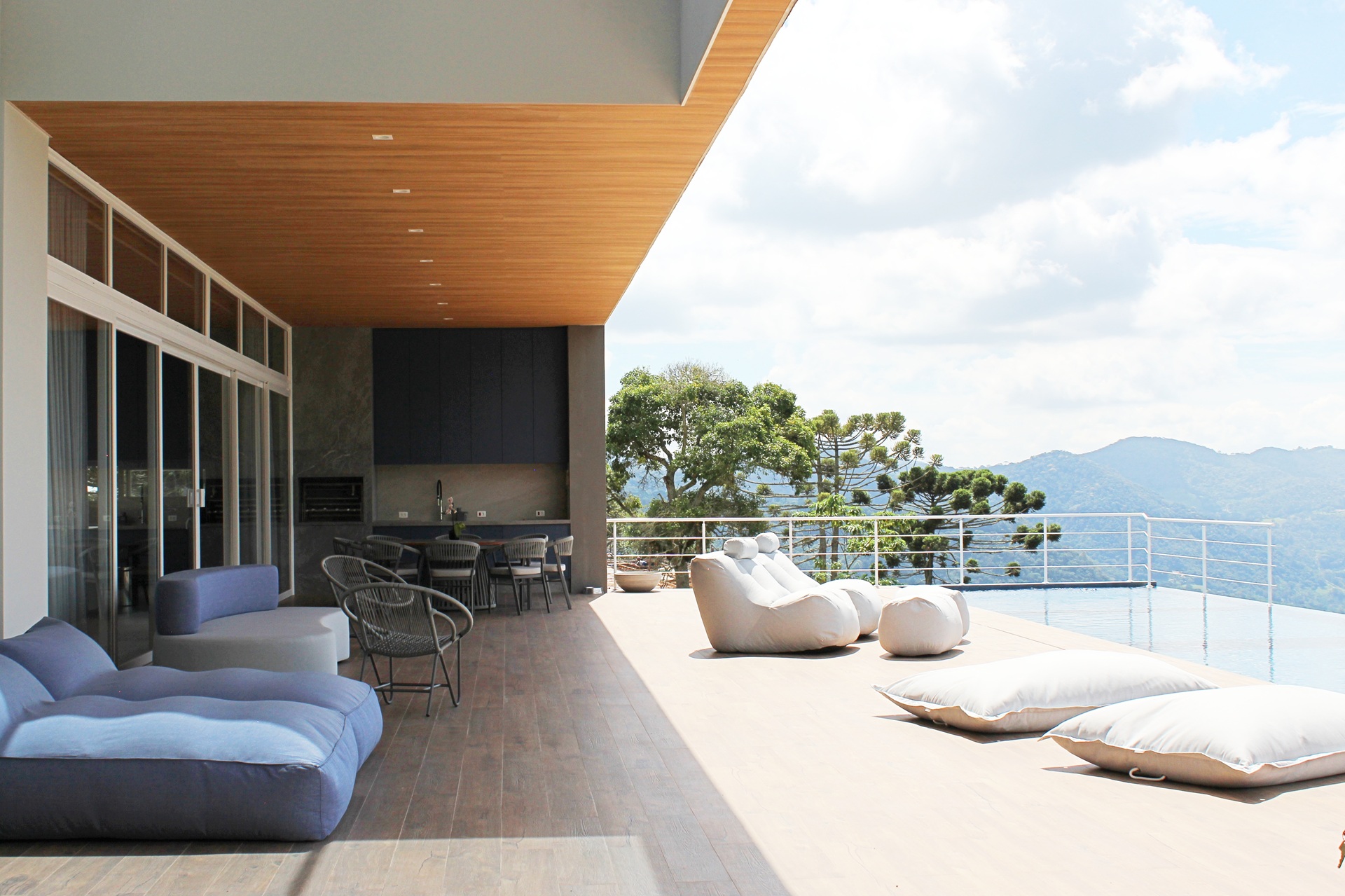 Varanda ampla com mobiliário contemporâneo e piscina infinita voltada para as montanhas, exemplo de arquitetura que valoriza a integração visual com a paisagem natural