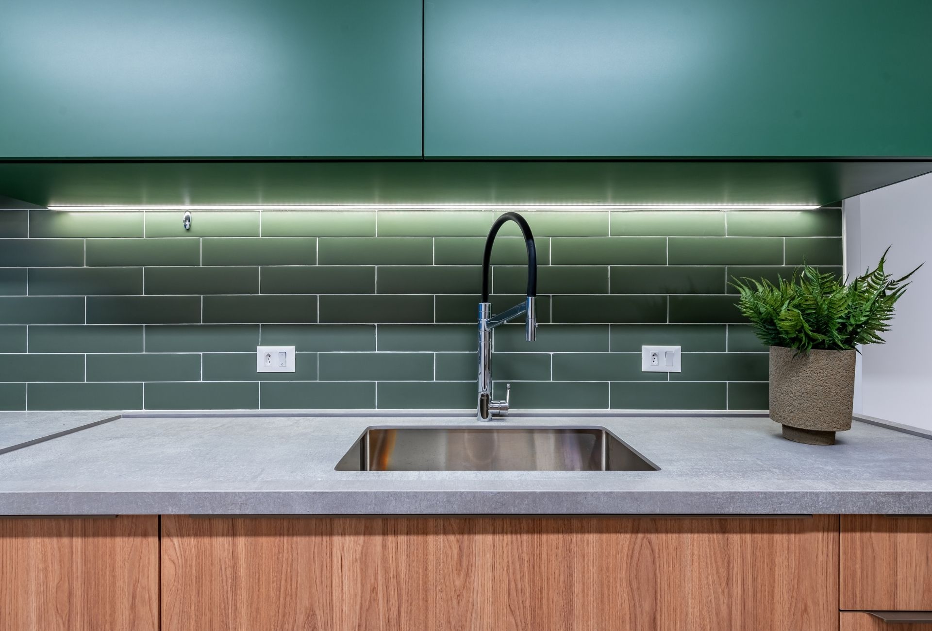 Cozinha com backsplash e armários superiores em tom de verde fechado