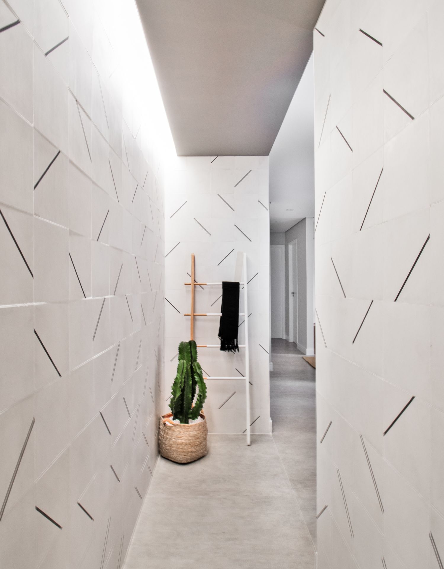 Corredor com parede texturizada e elementos simples, como cacto e escada, criam decoração simples