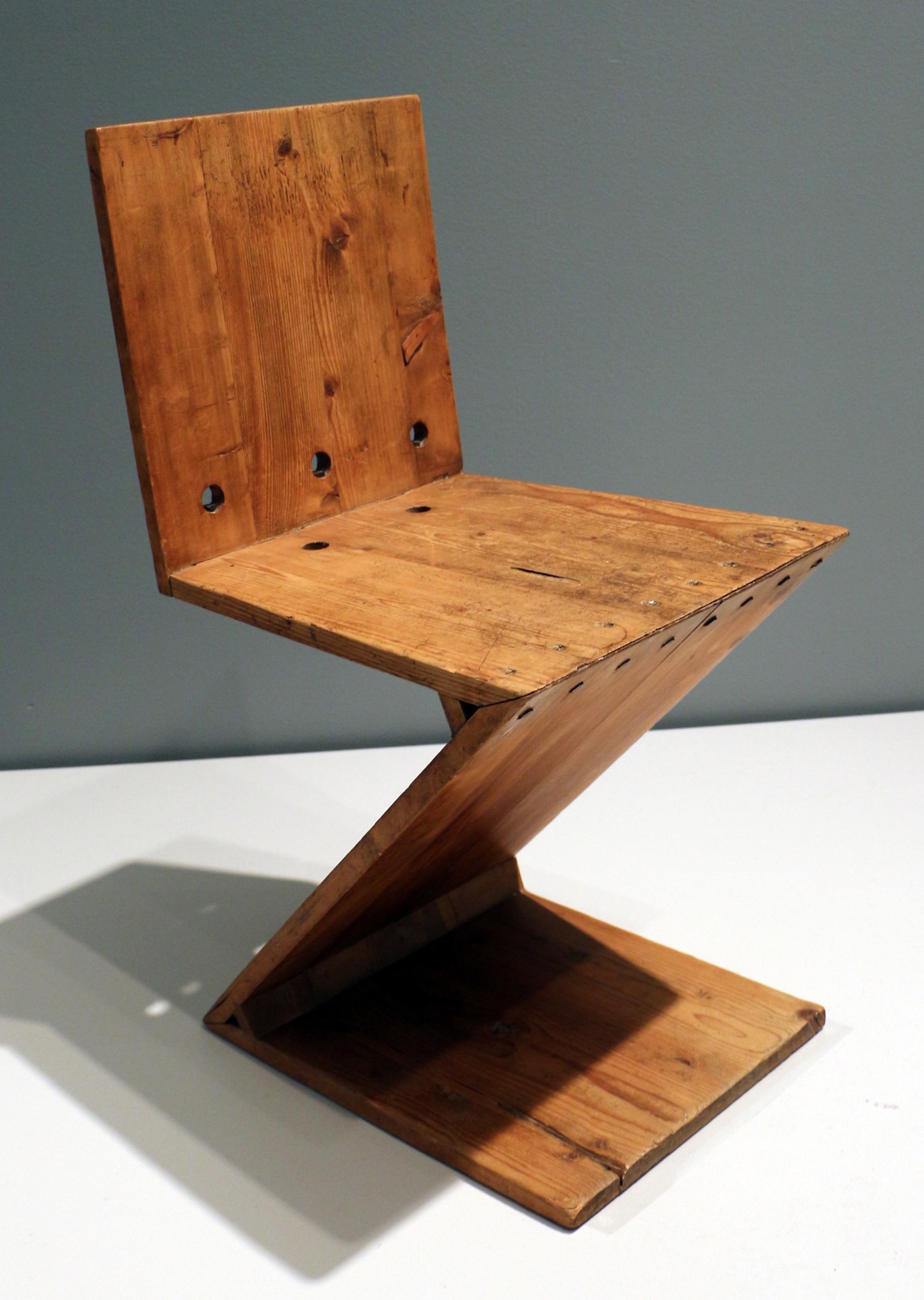 Cadeira Zig-Zag, projetada por Gerrit Rietveld entre 1918 e 1933 — peça icônica do movimento De Stijl, composta por quatro placas de madeira unidas em ângulos retos