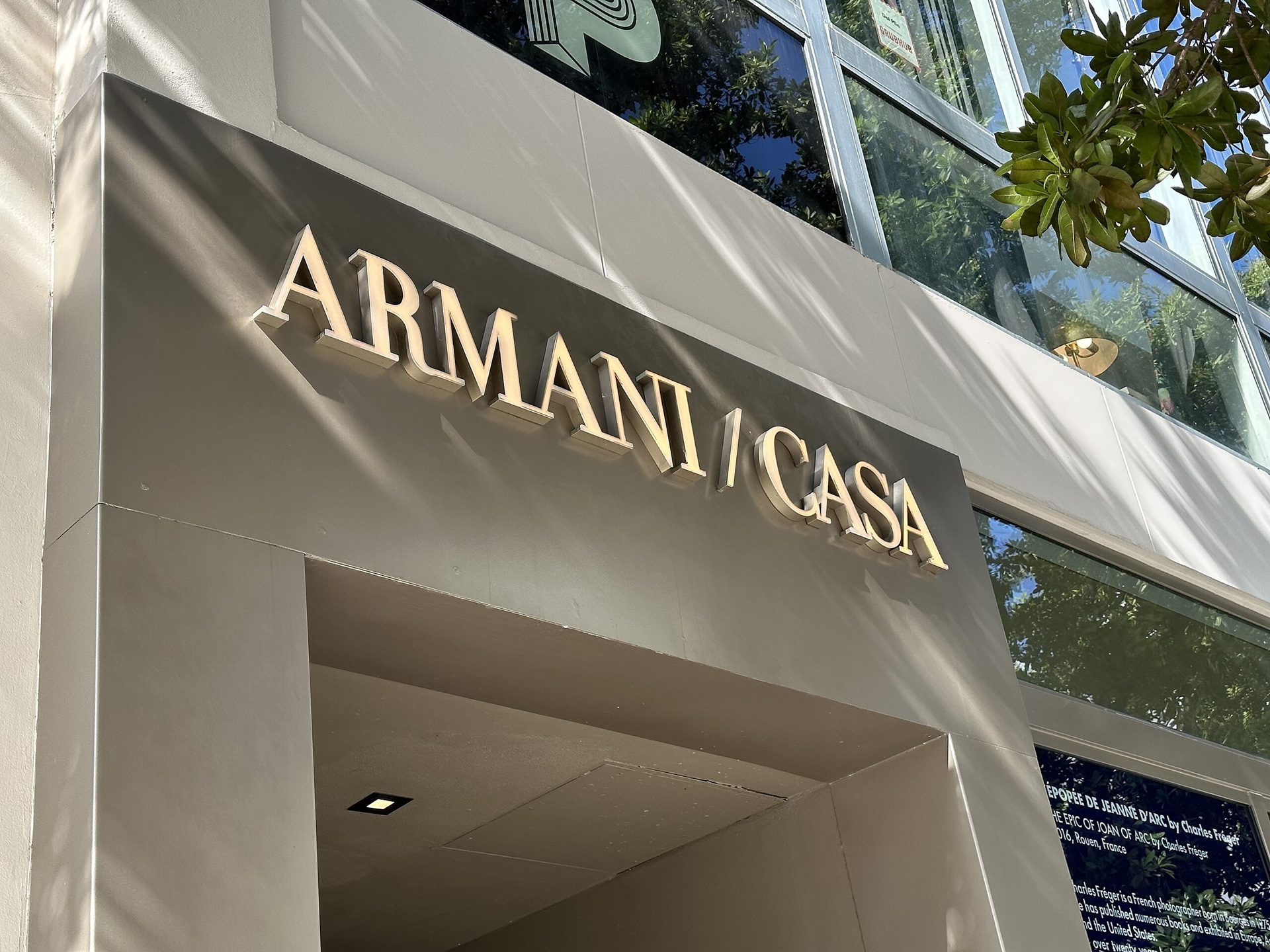 Entrada de uma loja Armani/Casa com fachada moderna em tons neutros e letreiro metálico iluminado