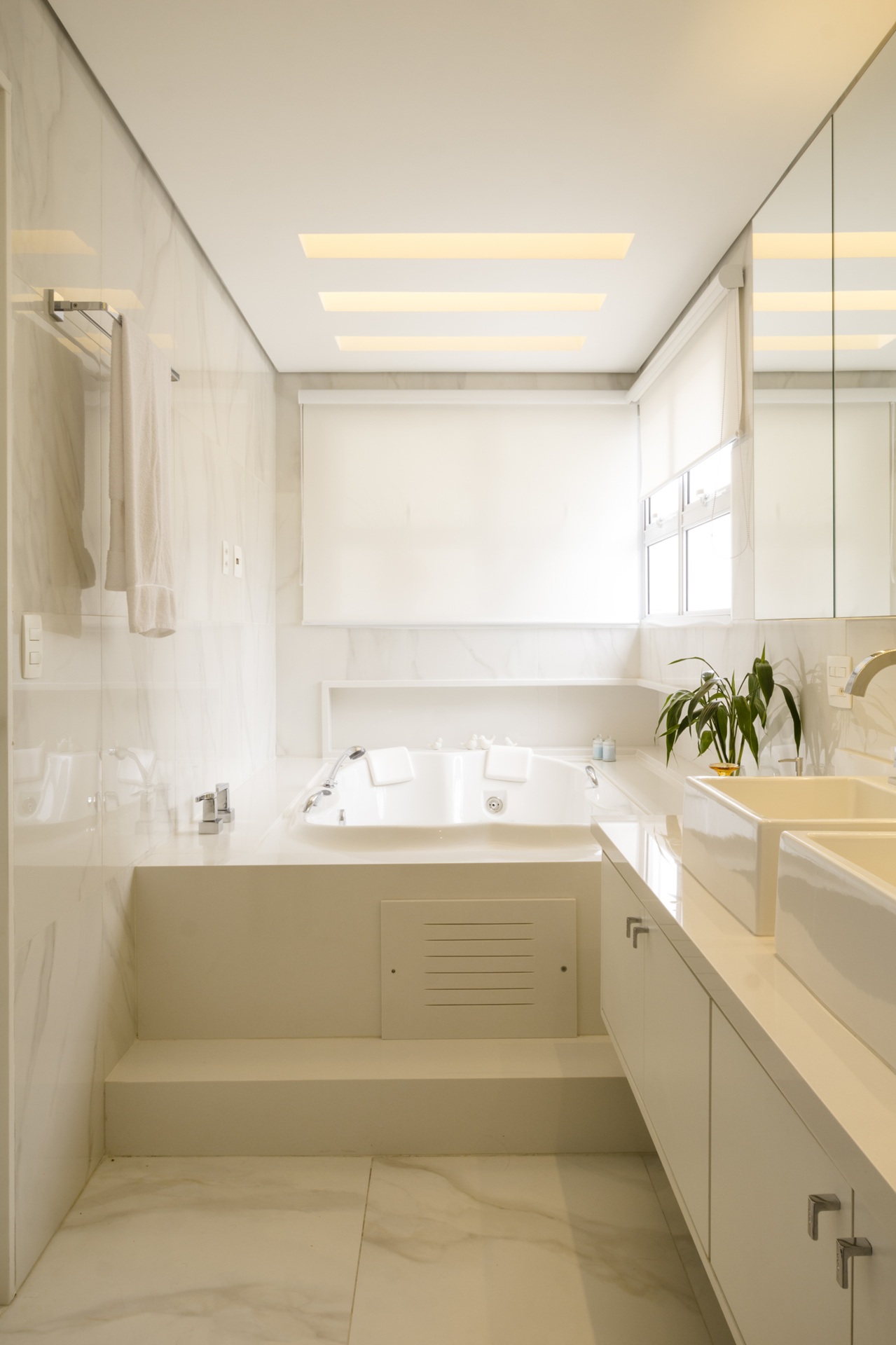Banheiro com revestimento branco de banheira de hidromassagem ao fundo