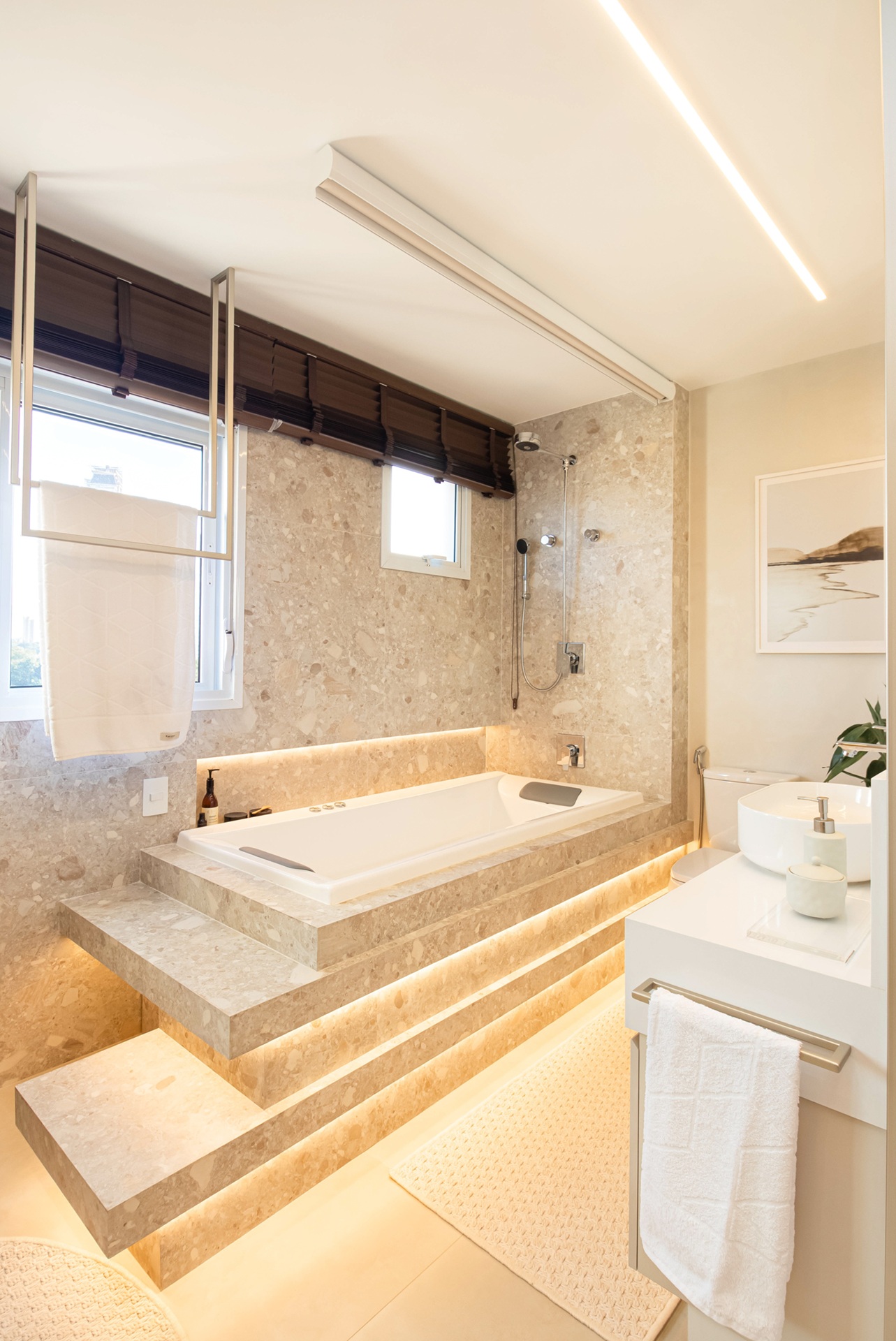 Banheiro com banheira de hidromassagem com entorno em porcelanato que reproduz mármore