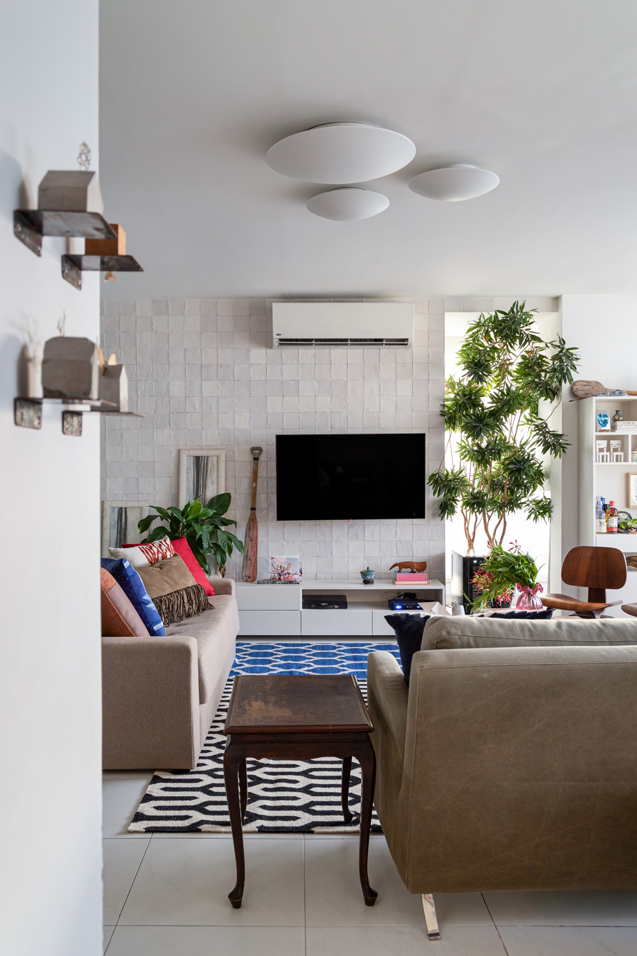 Sala de televisão com parede com revestimento texturizado branco ao fundo e ar-condicionado split