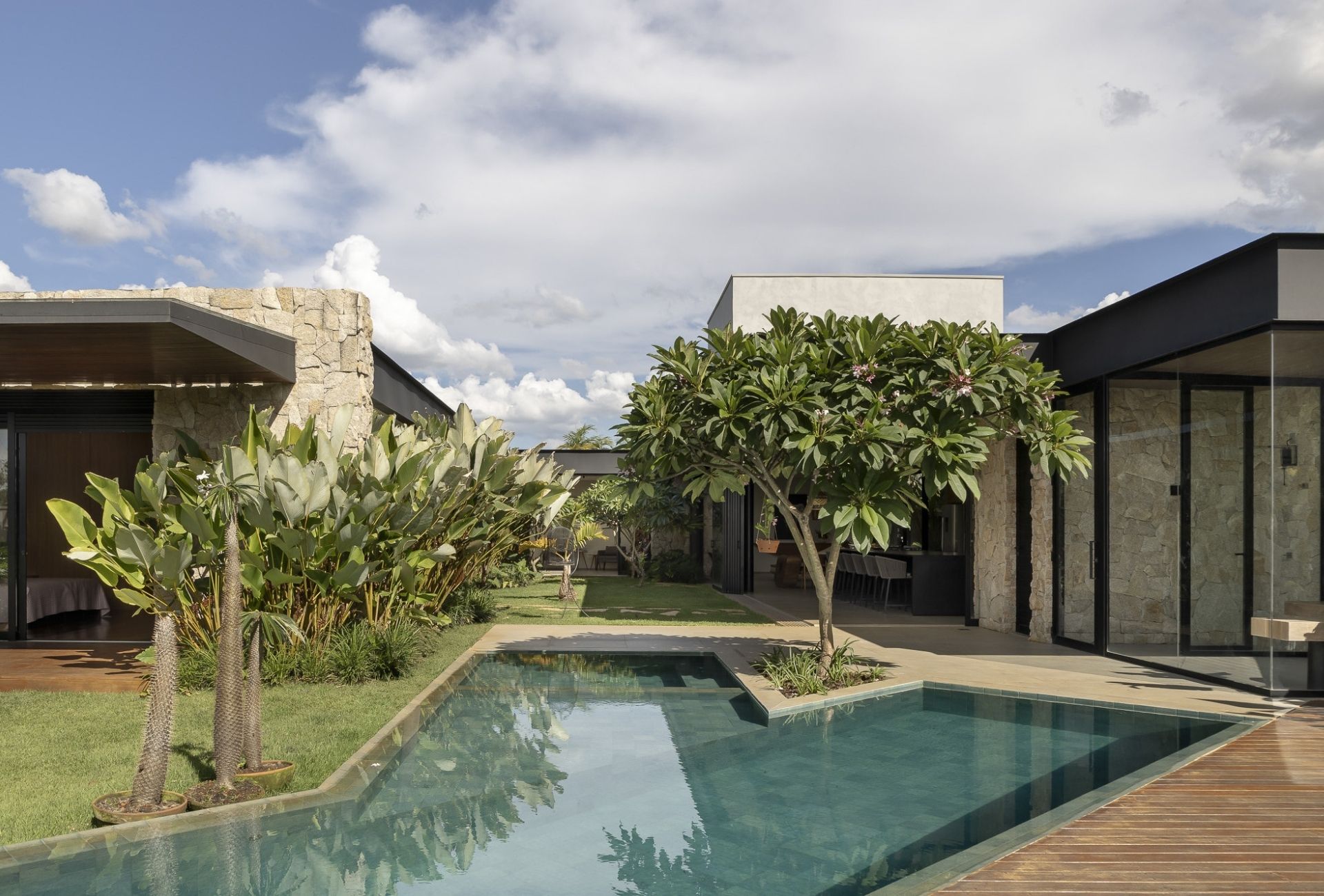 Imagem externa de uma residência com piscina e uma jasmim-manga compondo o paisagismo