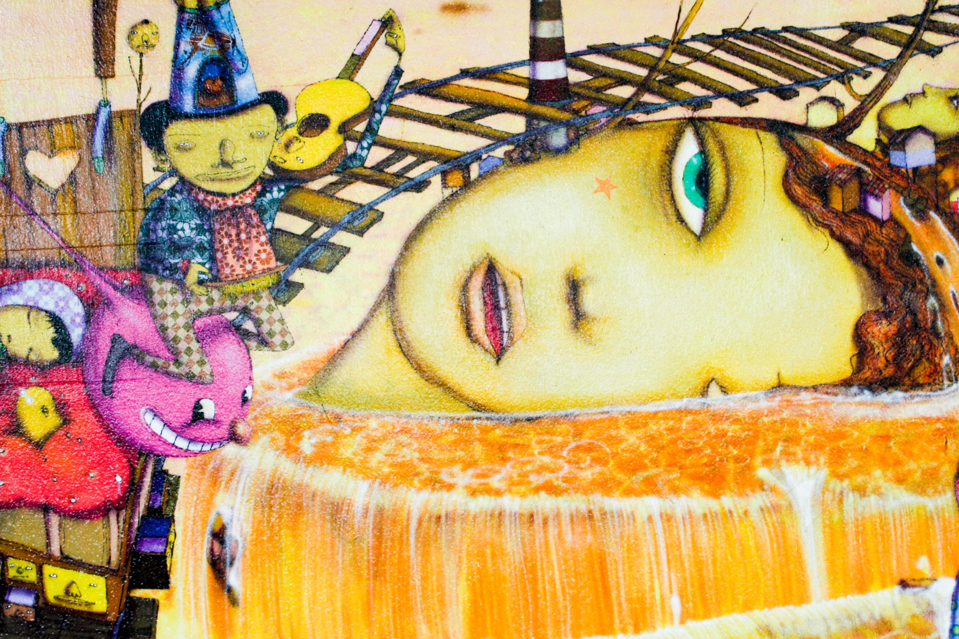 osgemeos A imagem mostra parte de um mural colorido com elementos fantasiosos: o rosto de uma mulher amarela deitada sobre uma superfície alaranjada que lembra uma cachoeira, um personagem pequeno com chapéu pontudo e violão, e criaturas rosadas de aparência divertida. Trilhos e objetos flutuantes completam o cenário surreal