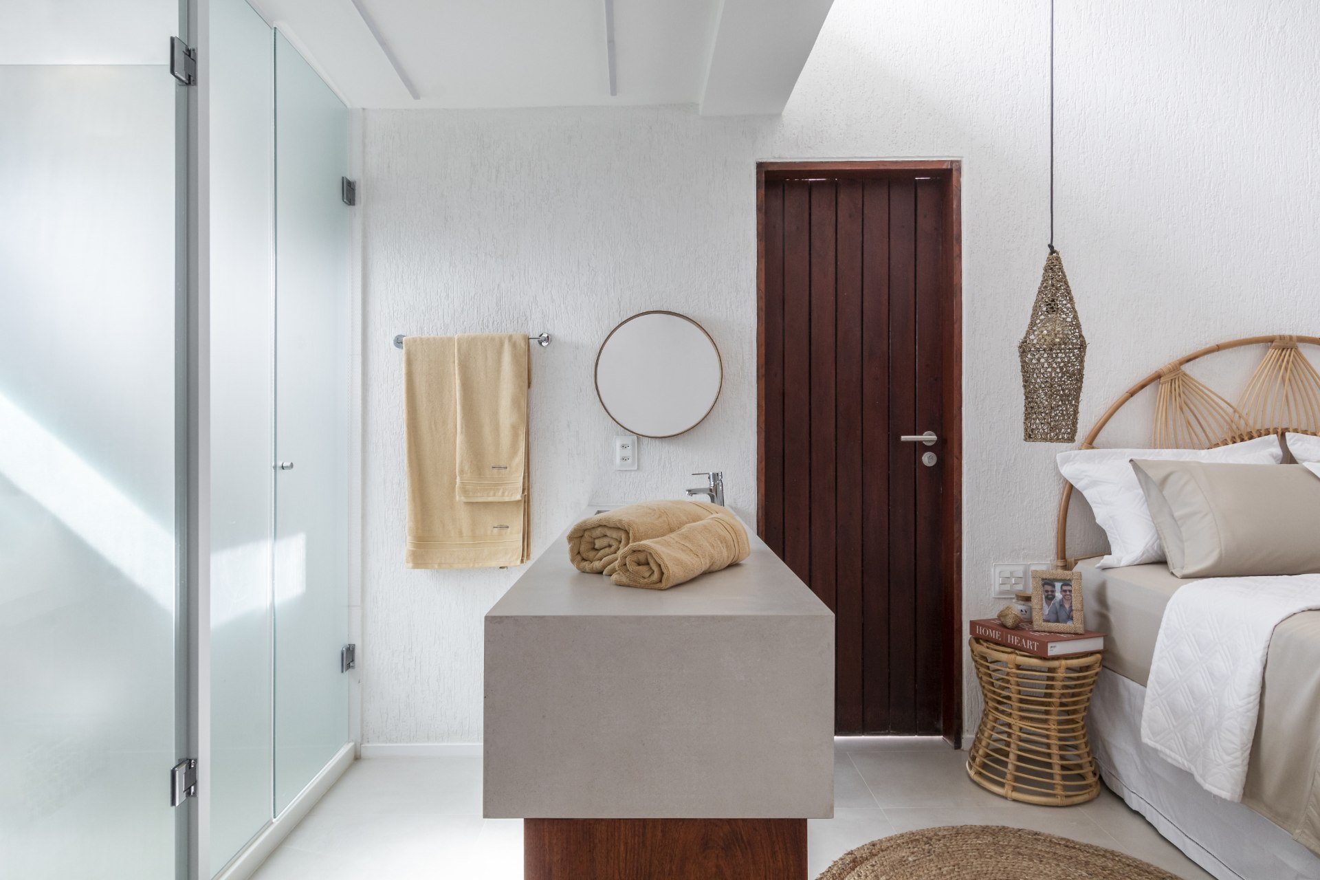 Quarto e banheiro sem parede divisória em suíte, decorados com elementos naturais