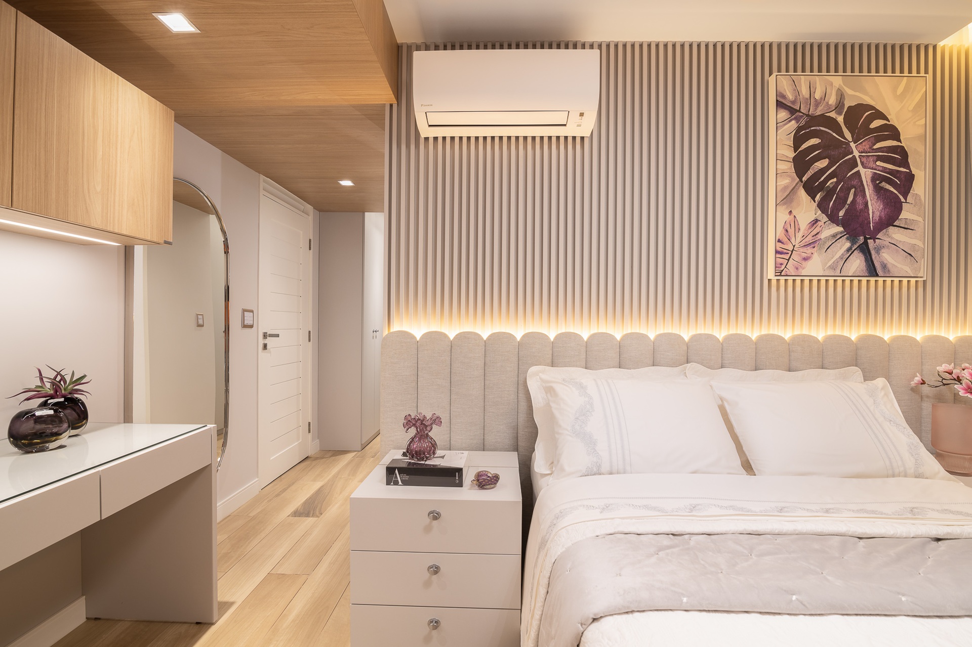Quarto com cama de casal, parede ripada atrás da cama e piso amadeirado