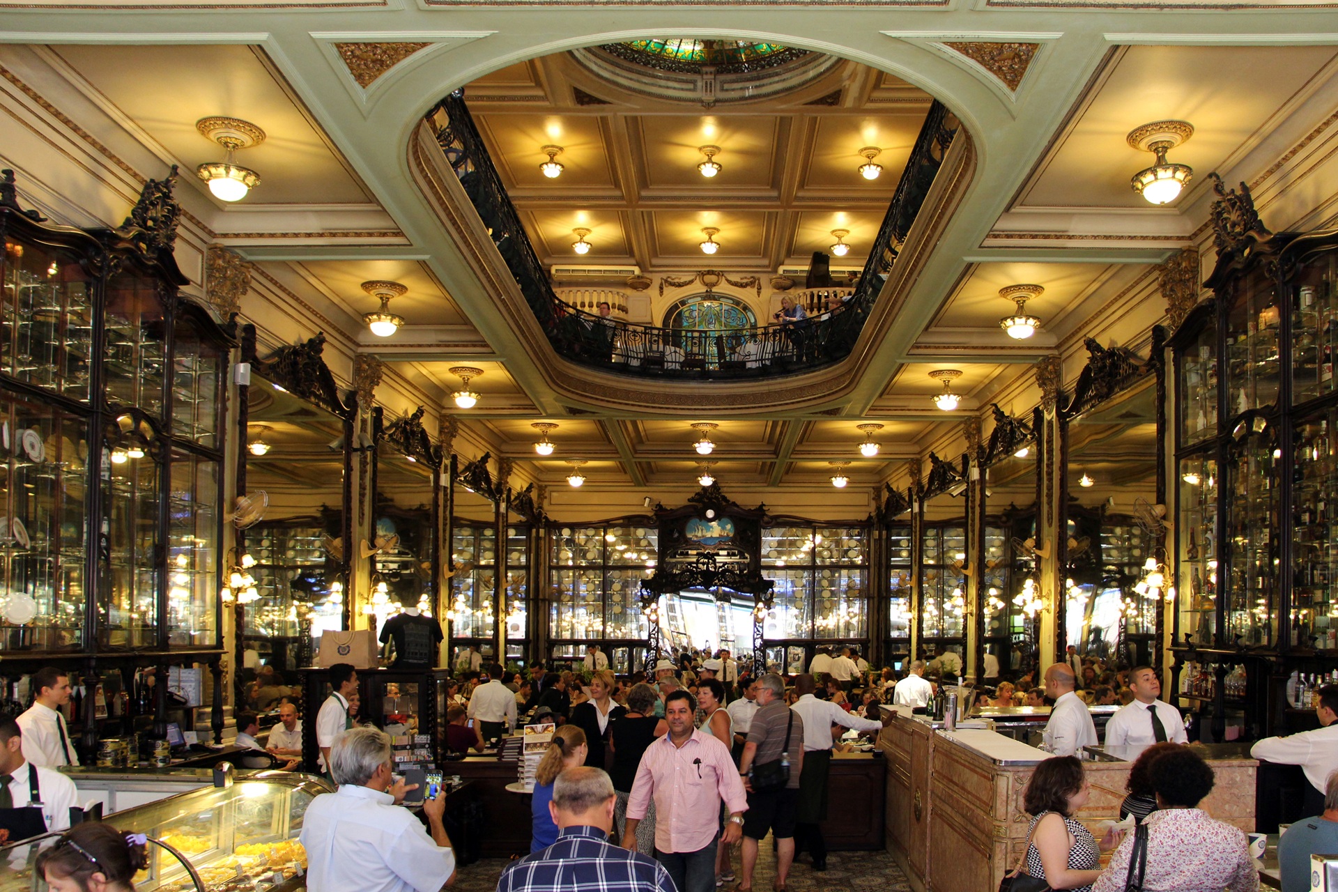 Interior da Confeitaria Colombo, no Rio de Janeiro, com decoração em estilo art nouveau, espelhos altos, balcões de mármore, vitrais coloridos no teto e um mezanino com grade de ferro